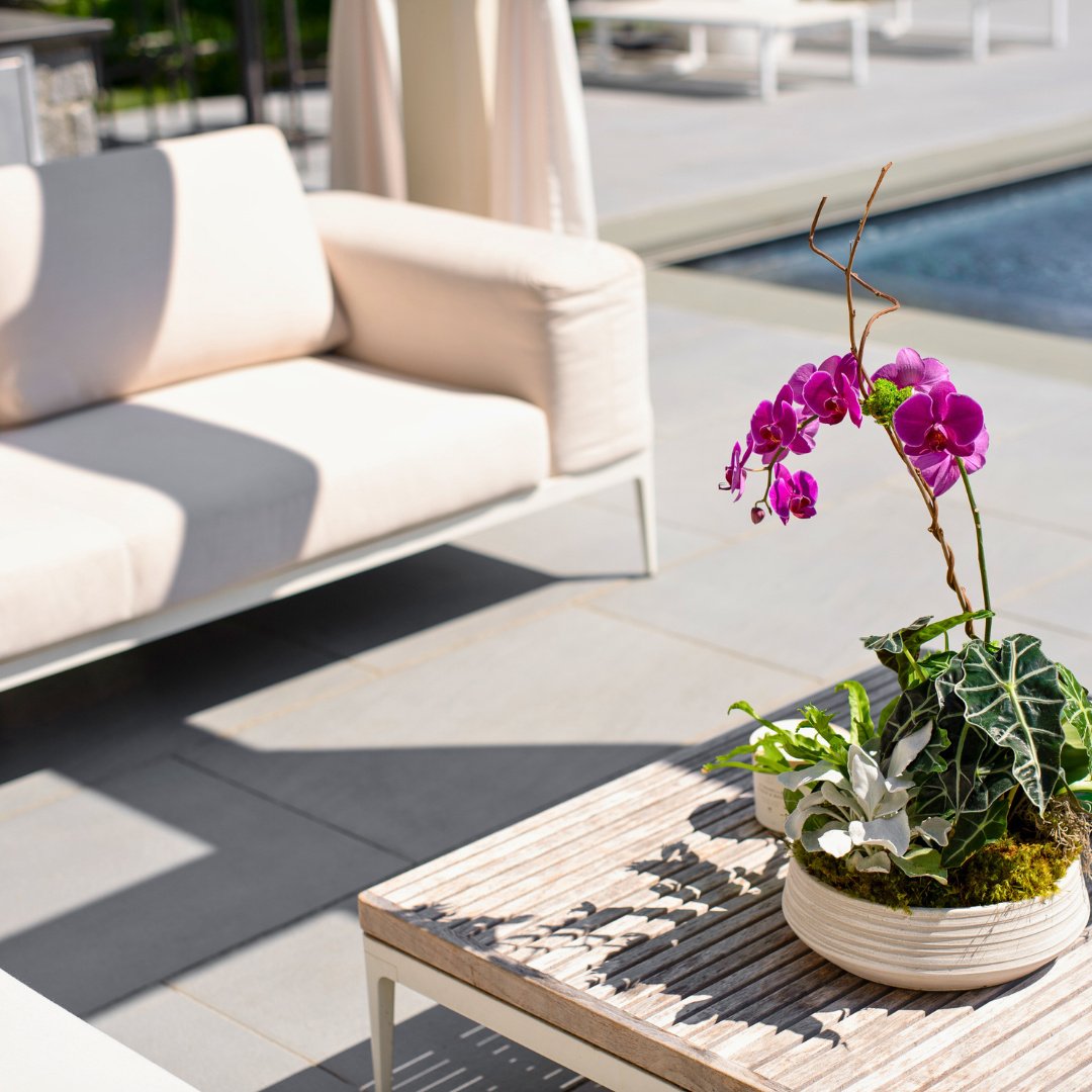 A simple touch of stone makes all the difference. This patio featuring The Gault Collection's Riverside Blue creates the perfect setting for outdoor dining, fresh flowers, and relaxed seating.