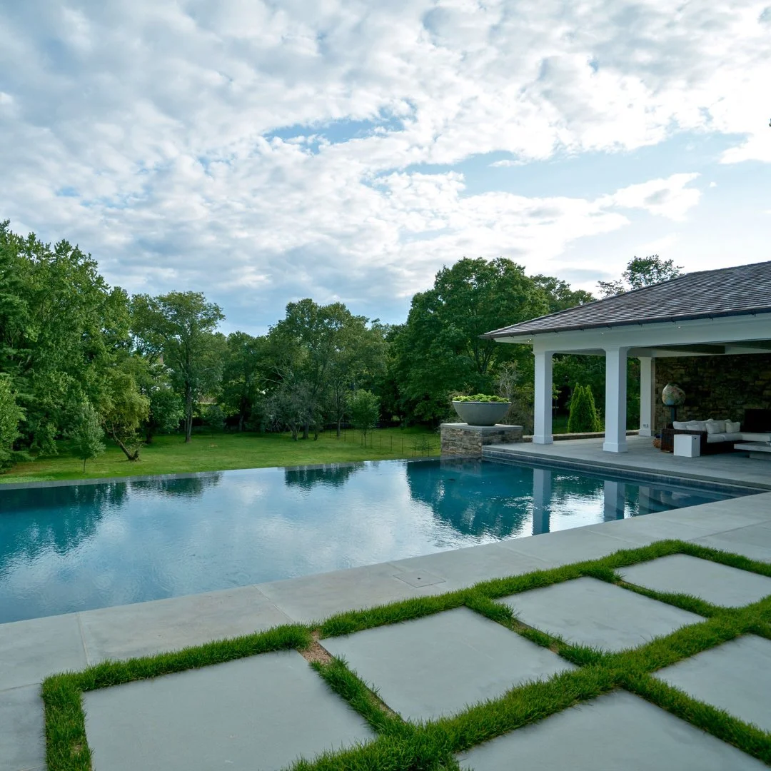 This Bluestone poolside patio, complete with a cabana, creates a seamless outdoor retreat. With the sky mirrored on the water, it&rsquo;s a picture-perfect setting made for relaxing days and unforgettable evenings.