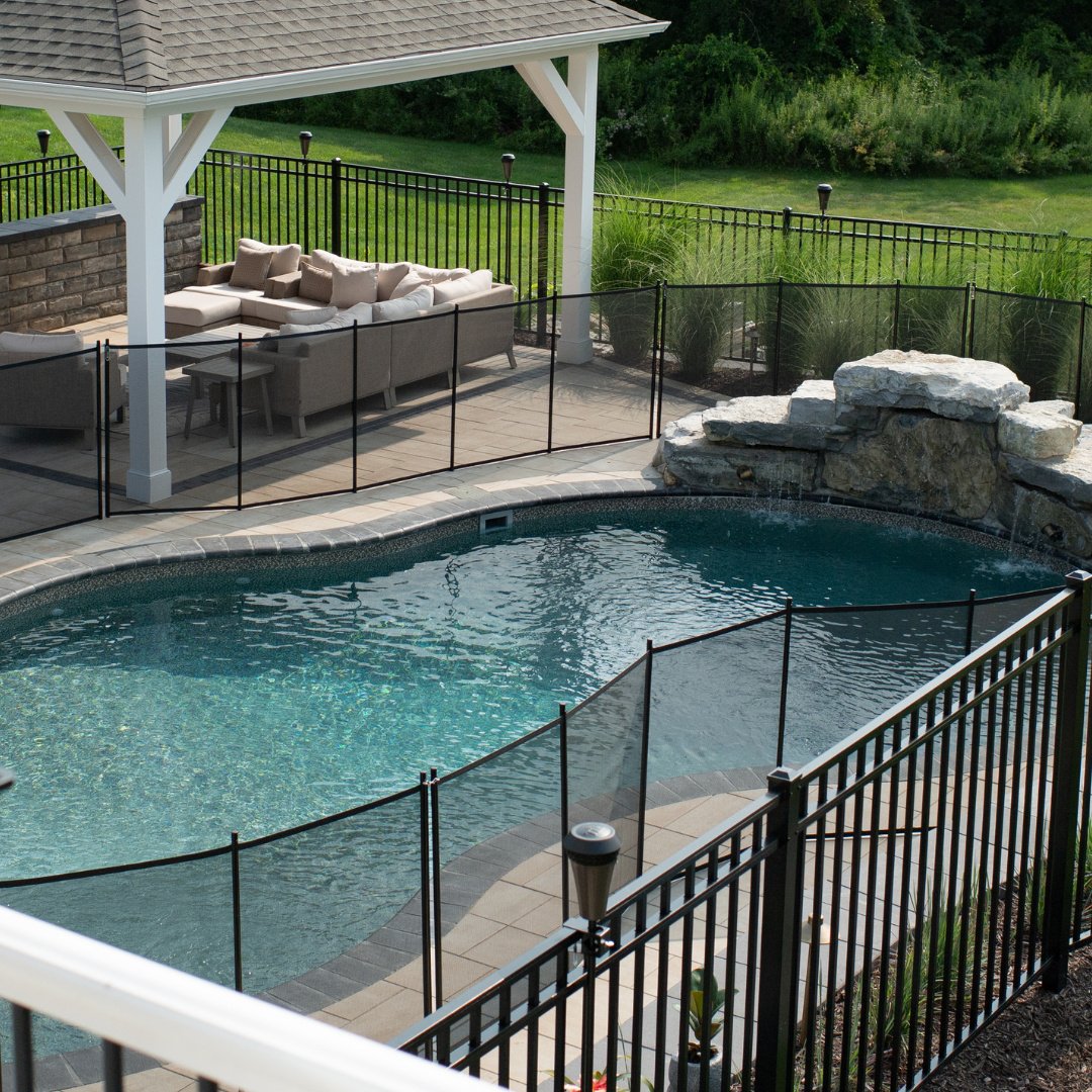 A view from above, where design and safety meet nature.
From atop the rock formation, a waterfall cascades below into the pool, surrounded by sleek Unilock Pavers with bullnose coping- creating a backyard oasis that&rsquo;s both stunning and family-f