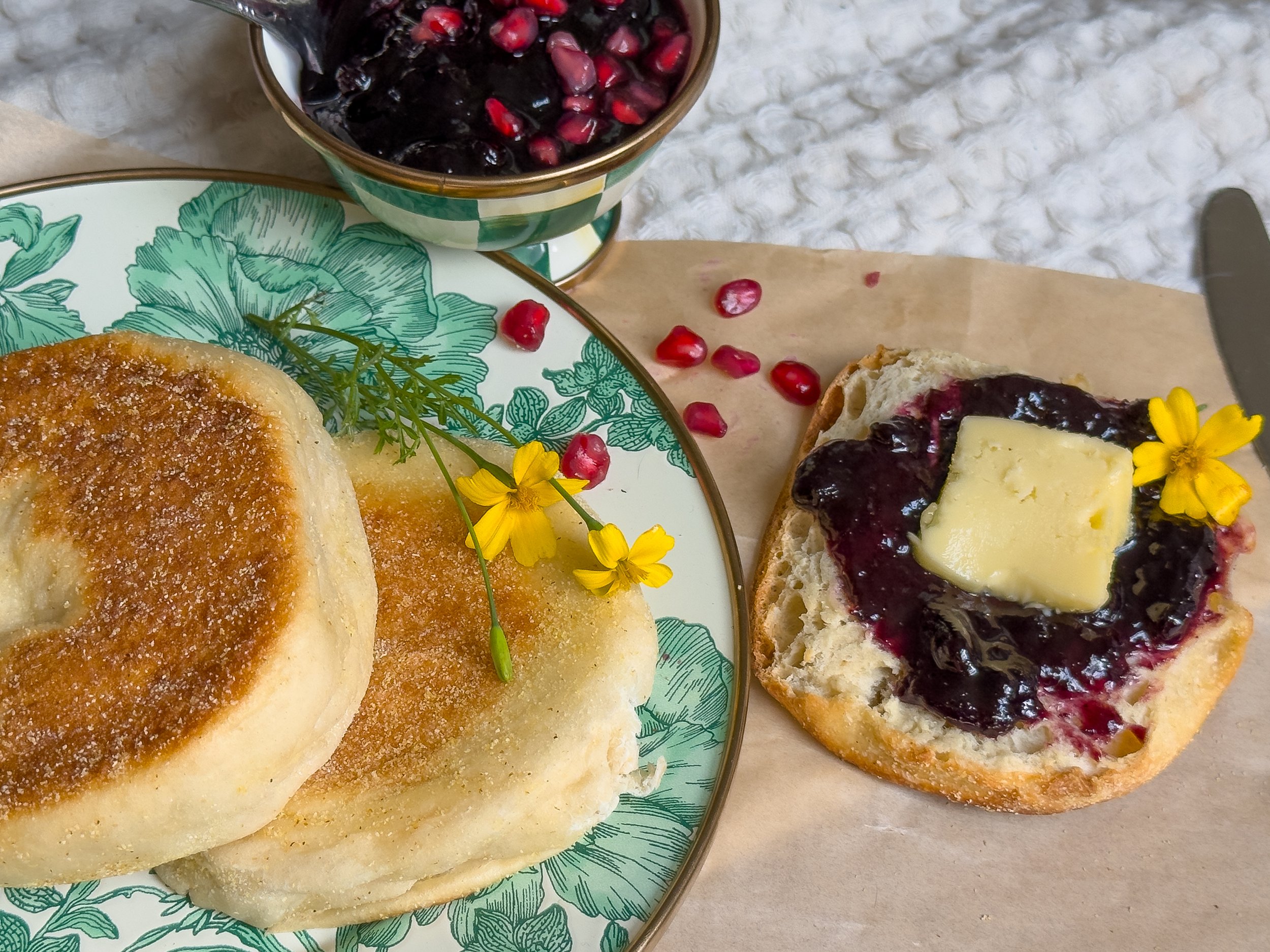 Golden homemade English muffins cooling on a rack, dusted with semolina