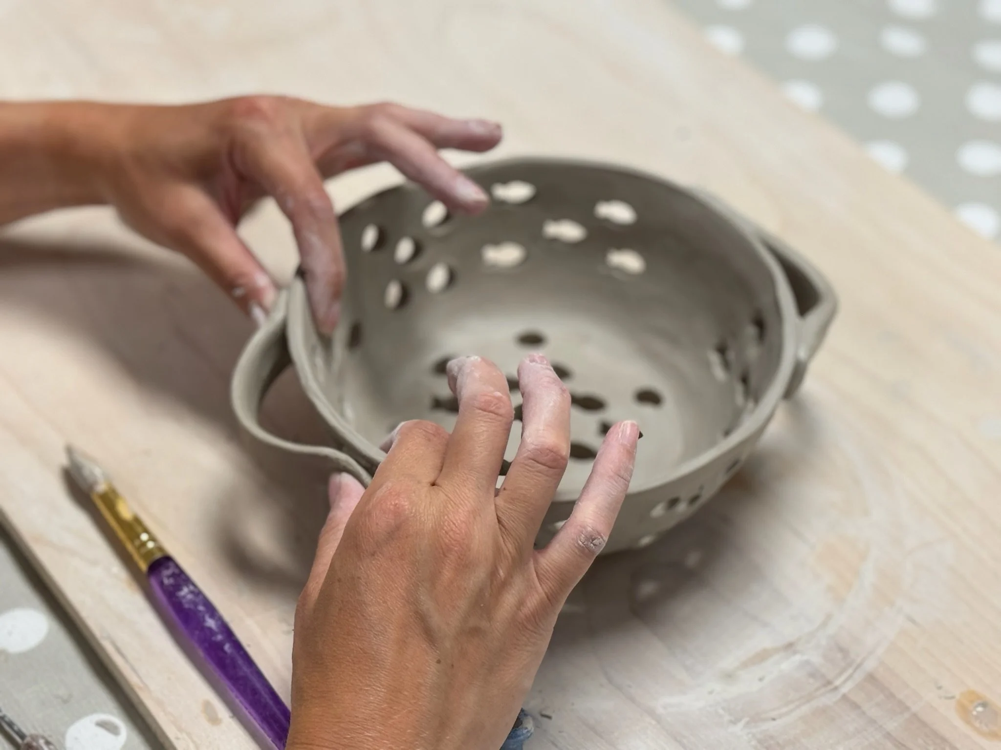 Hands building a colander pot