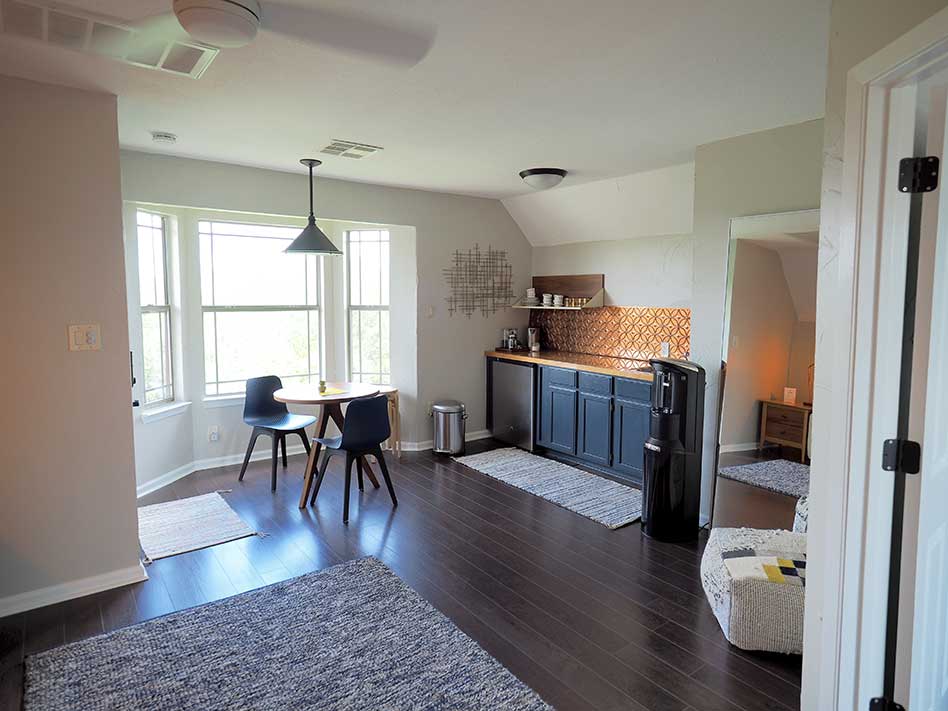 Apartment kitchenette includes a small fridge, water cooler, and sink