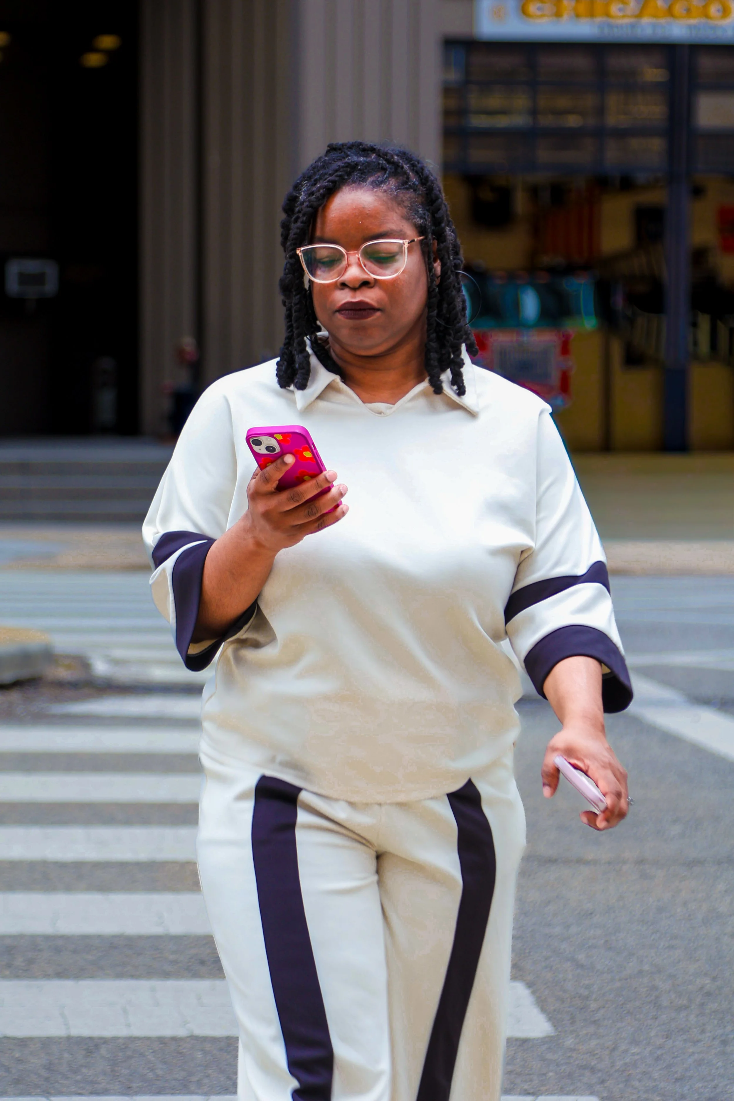 Black woman entrepreneur holding phone while walking across the street in a Chicago branding photoshoot
