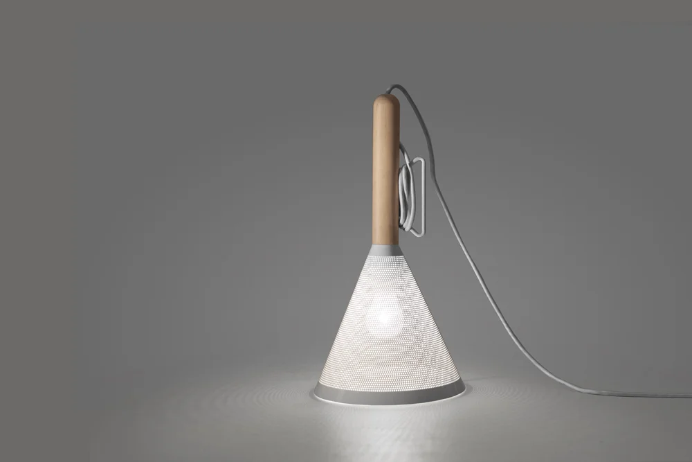 Signal Lamp Client: Fab 2014 The Signal lamp was designed to be and adjustable height pendant or sculptural table lamp. The cord enters through the top of the handle and exits on the side next to a metal bracket which the cord can be wound around to shorten its length.