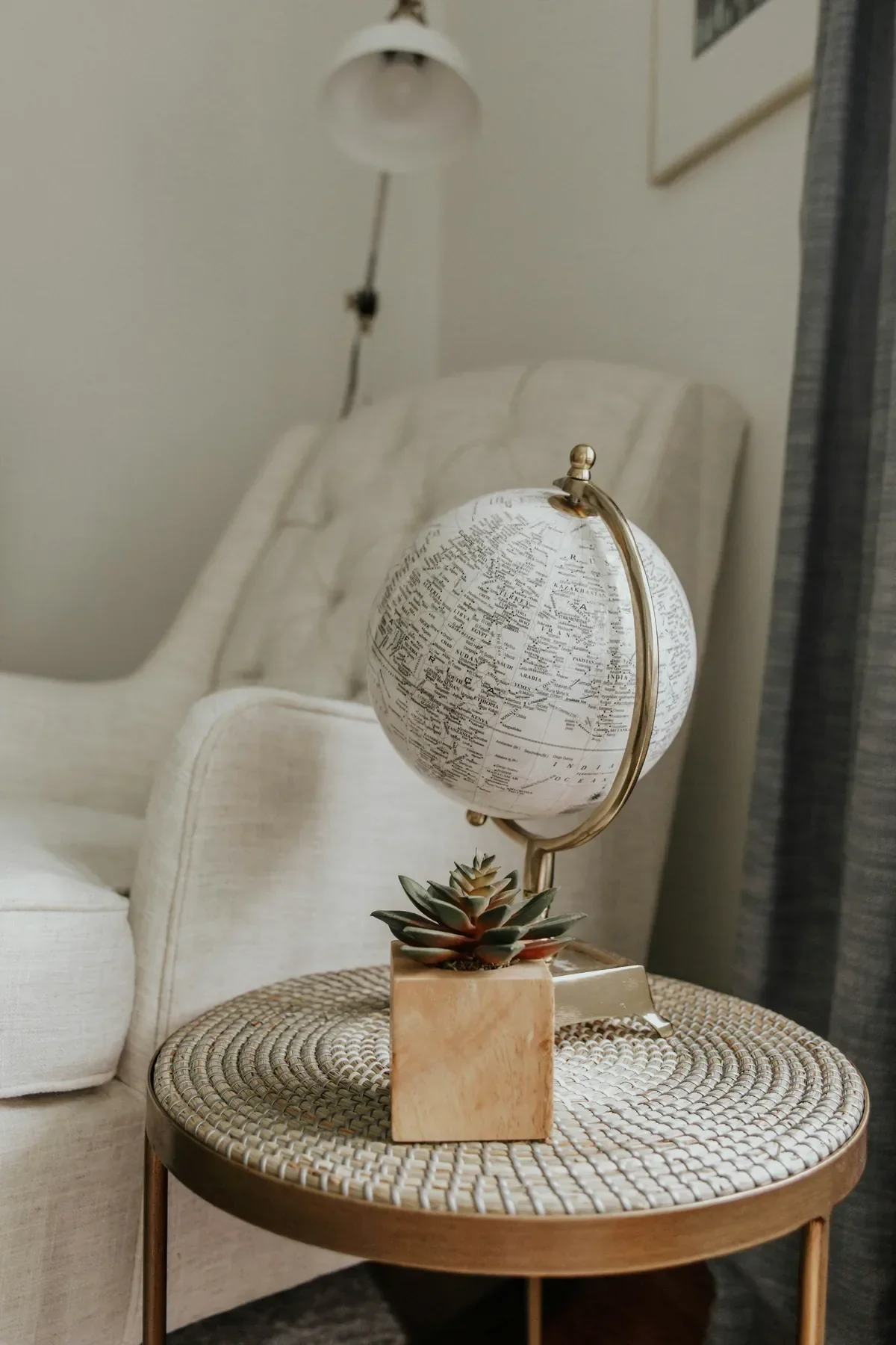White globe with gold stand on a side table in a cozy living room, symbolizing sabbatical travel dreams