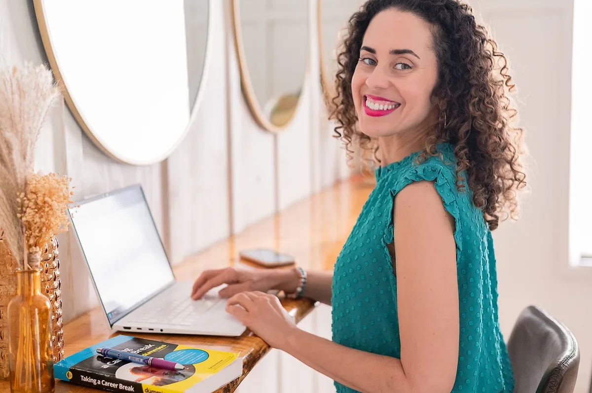 Katrina McGhee typing on laptop with Taking a Career Break for Dummies book on desk