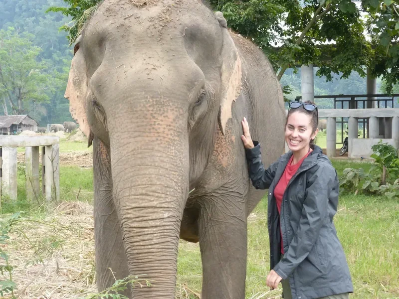 Sabbatical coach Katrina McGhee smiling beside an elephant at a sanctuary during her own sabbatical