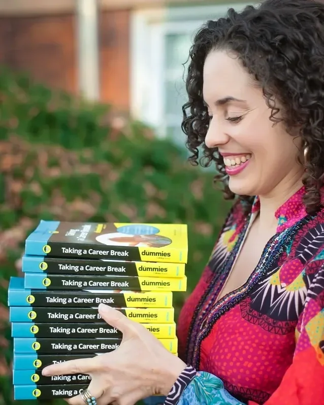 Katrina McGhee laughing while looking down at a stack of Taking a Career Break For Dummies books