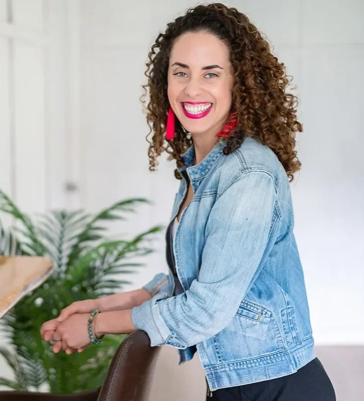 Katrina McGhee career break coach laughing beside laptop at wooden desk with plants