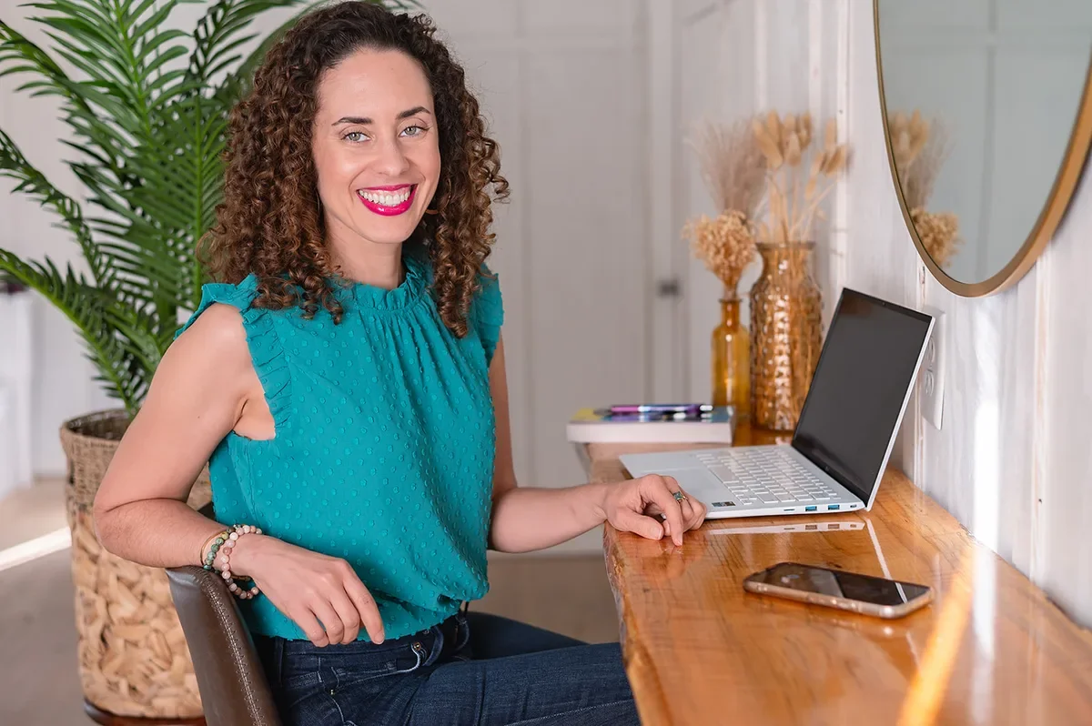 Katrina McGhee smiling at desk with laptop in a bright home office, career break coach