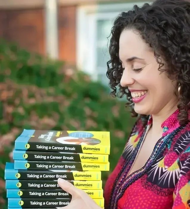 Katrina McGhee laughing while looking down at a stack of Taking a Career Break For Dummies books