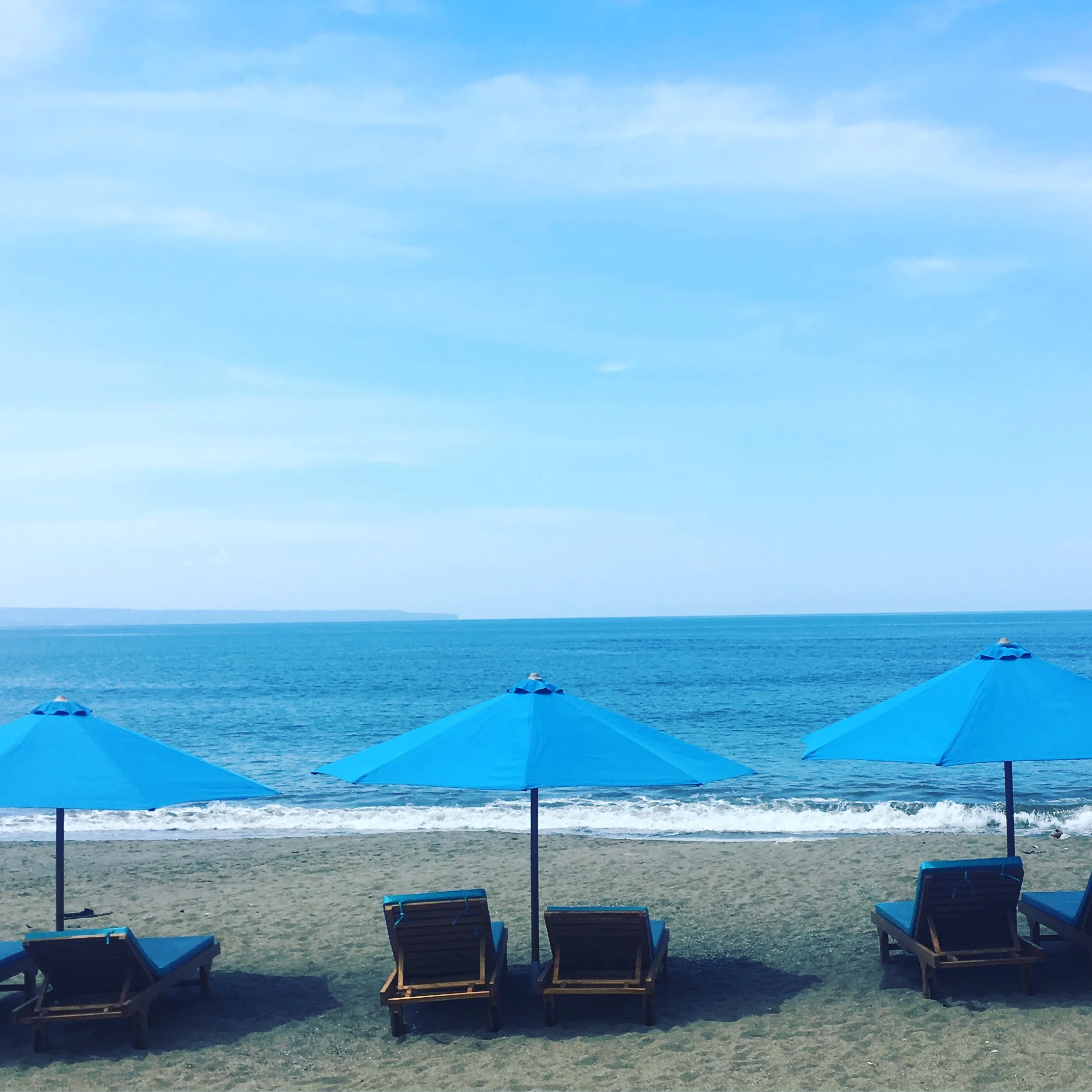 Beach scene with blue umbrellas and lounge chairs