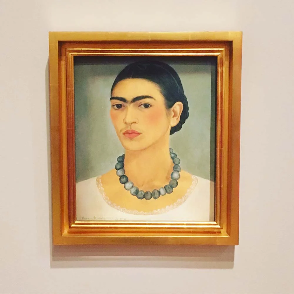 Framed portrait painting of a person wearing a blue necklace.