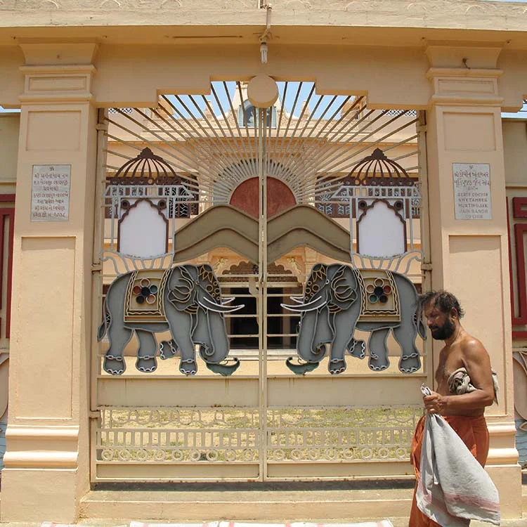 Decorative gate with elephant designs and a person walking by