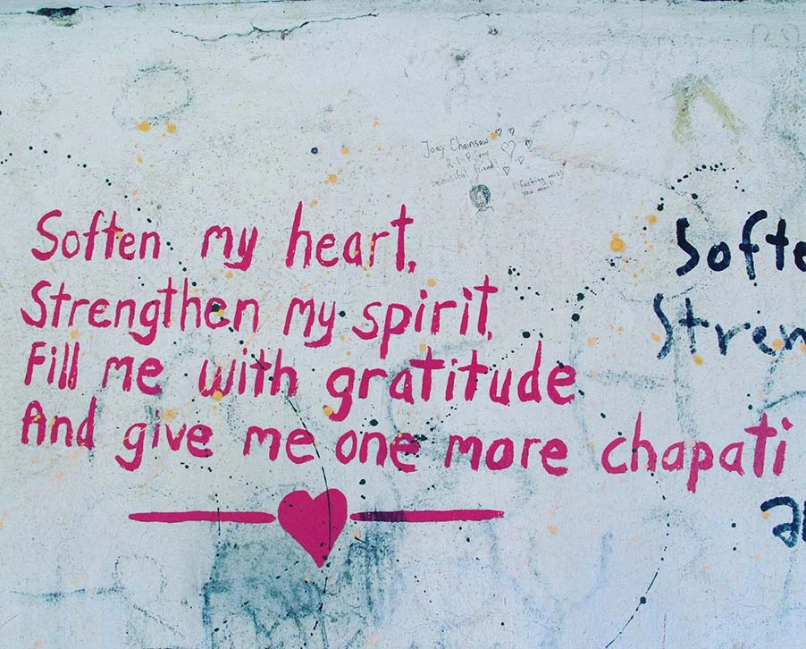 Inspirational quote on a wall: 'Soften my heart, Strengthen my spirit, Fill me with gratitude, And give me one more chapati' in pink letters with a heart graphic.