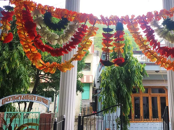 Colorful garlands hanging outdoors, with buildings and trees in the background.