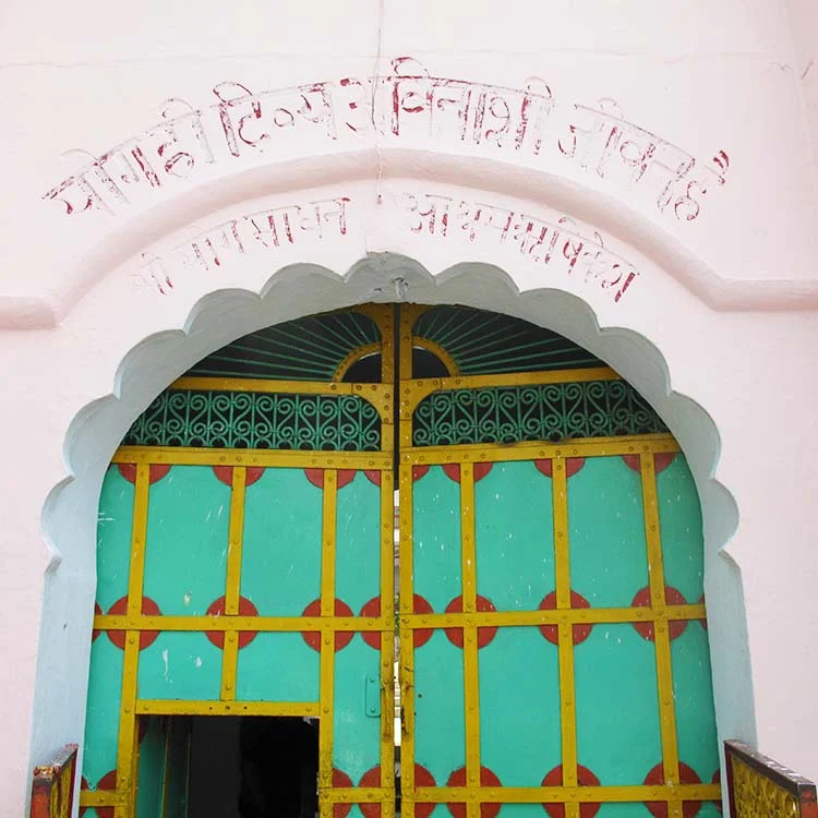 Ornate green and yellow arched door with Hindi script above, India