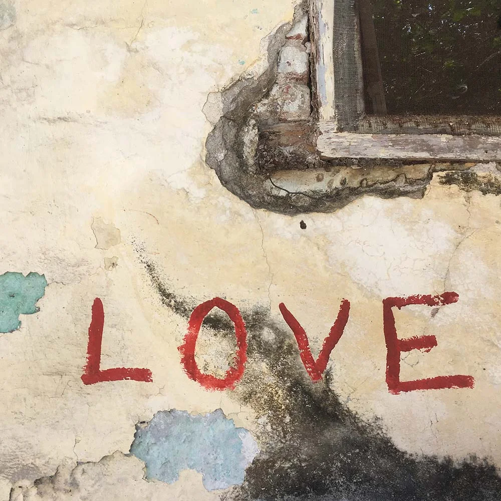 Peeling wall with "LOVE" graffiti in red near window