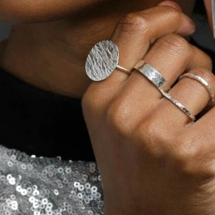 Close up of hand showing flat textured silver ring worn on middle finger