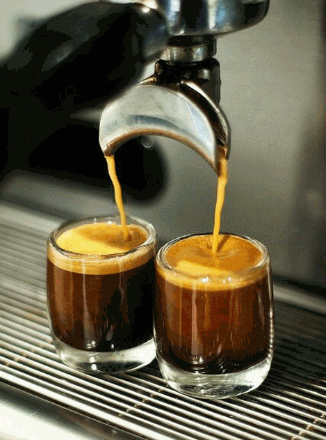 Espresso shots being poured into two glass cups.