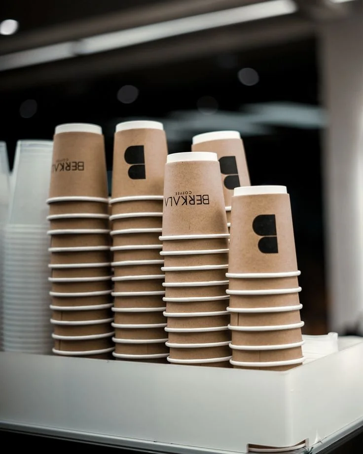 Stacks of paper coffee cups in a tray at a cafe.