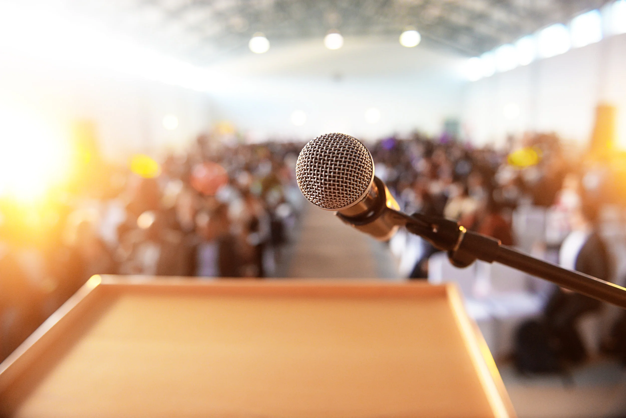 Microphone-in-front-of-podium-with-crowd-in-the-background-614138202_6016x4016.jpeg