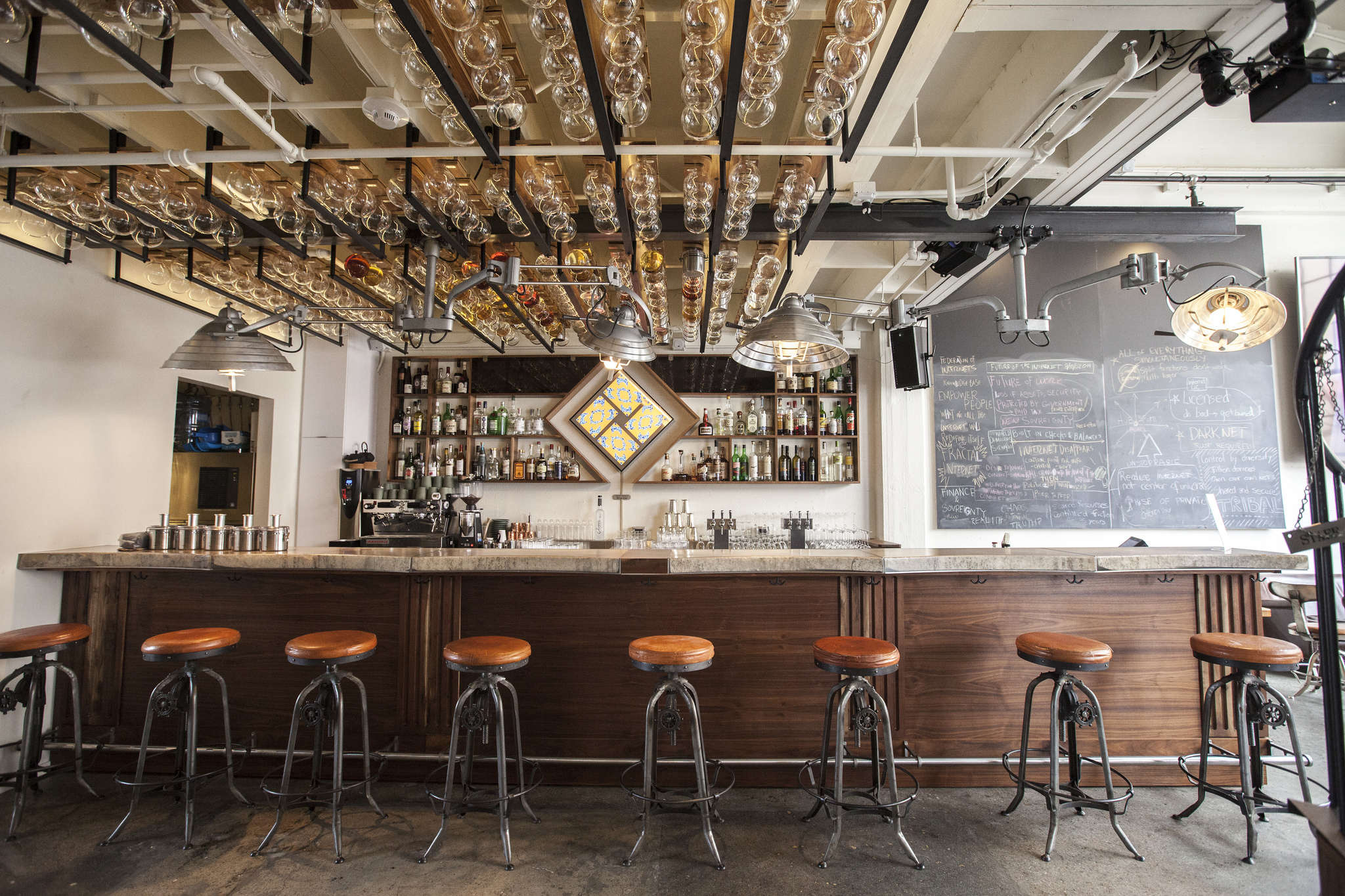 Directly above the bar hangs an intricately designed ceiling storage unit for The Interval’s bottle club program. We designed and fabricated the ceiling mounted bottle holders, which in the night become illuminated from above, casting a twinkling, glowing effect among the bottles.