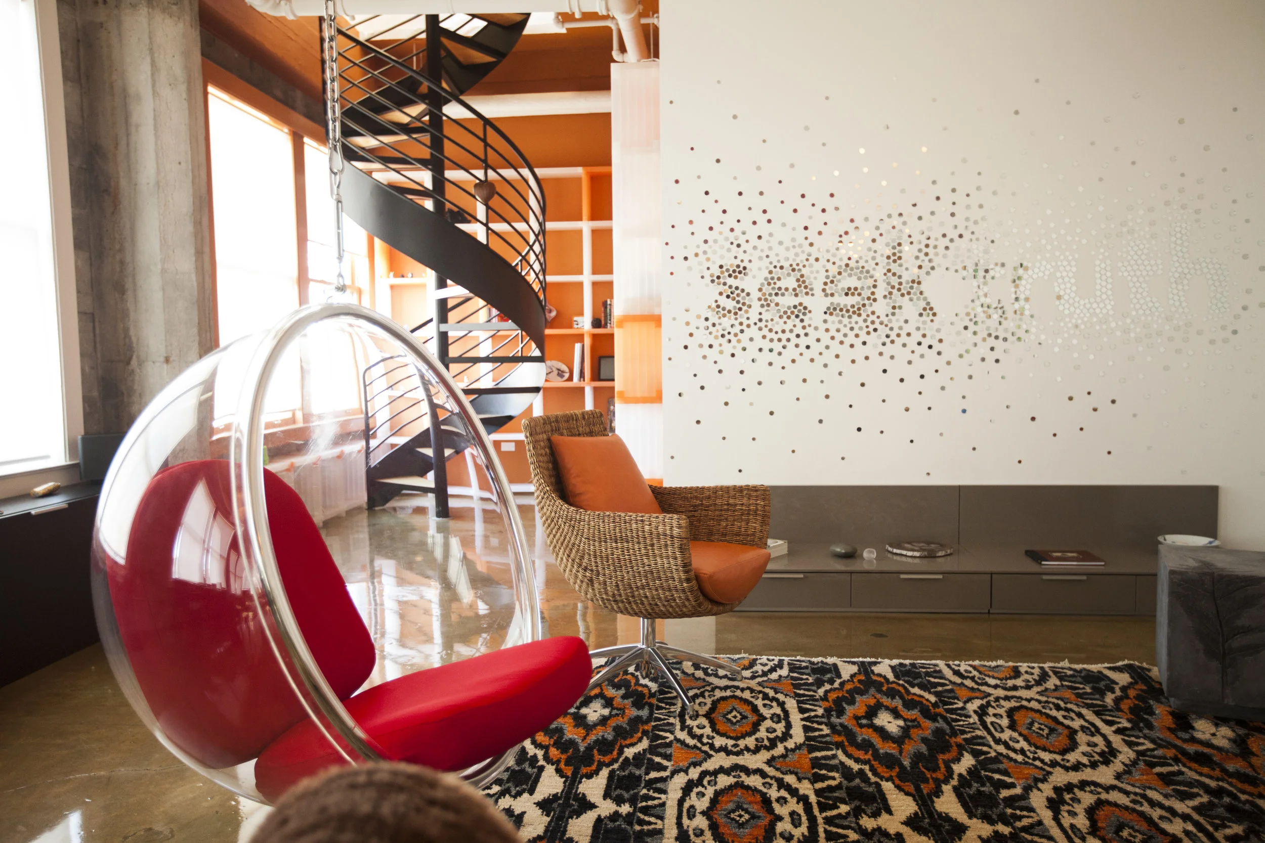 A classic mid-century hanging bubble chair floats above the polished concrete floor.