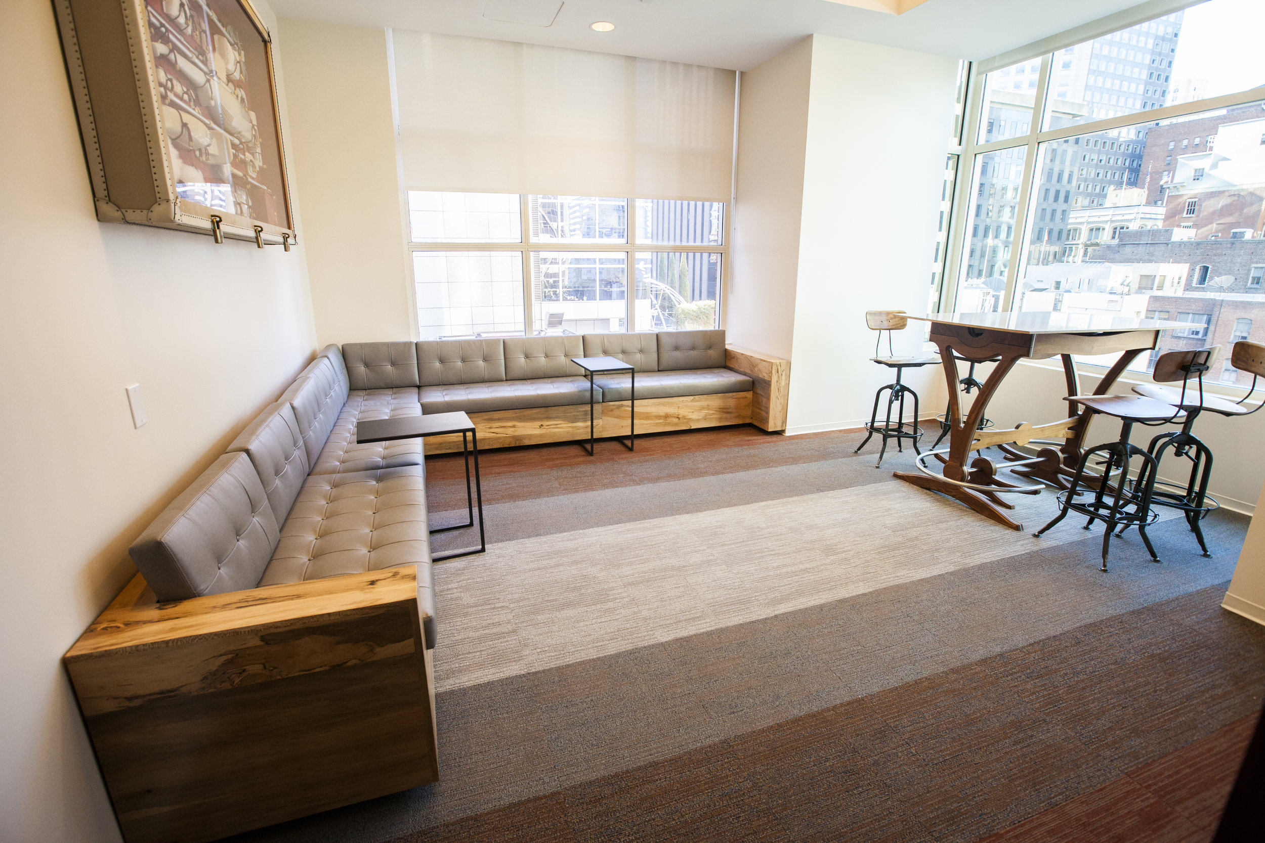  The rest of the main meeting room is filled with multi toned carpeting of rusty red, grey and blue. Our custom couch wraps the room and the standing work table sits by the large window. 