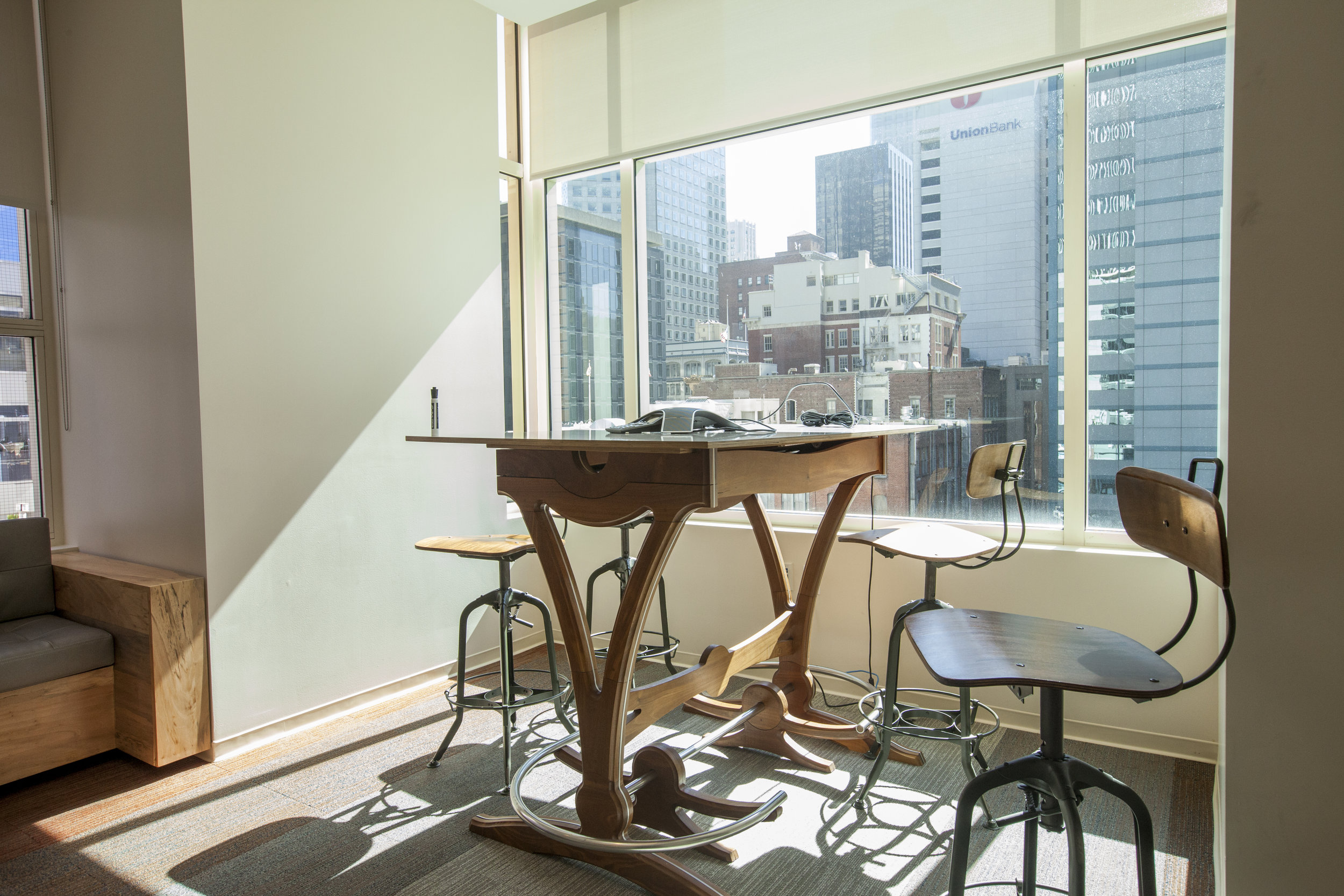  A standing height work table by the window allows multiple kinds of meetings in this sun light room. 