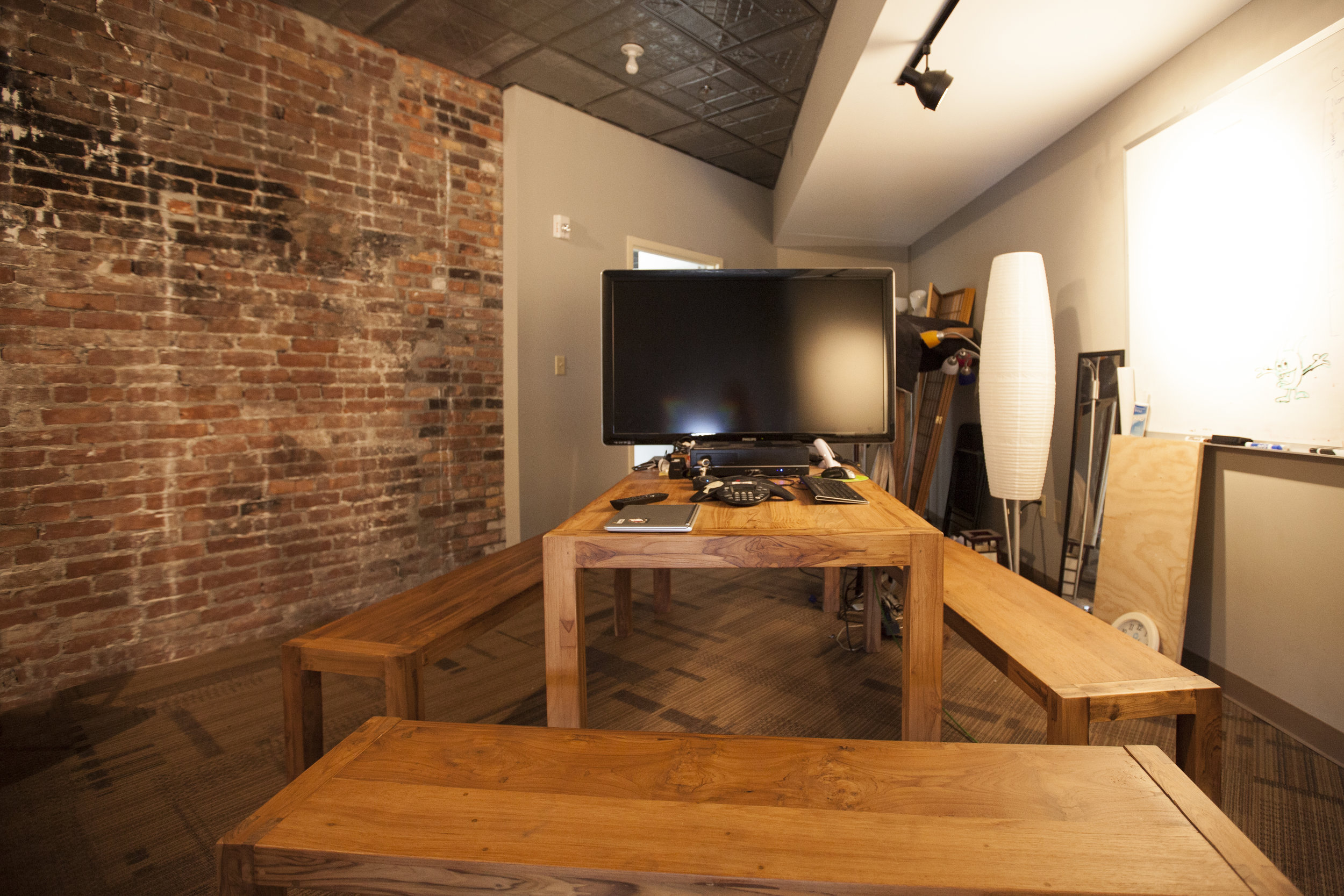  Other small and difficult spaces needed quick and affordable make overs to become meeting spaces. This room has the original brick wall exposed and hardwood furniture installed. 