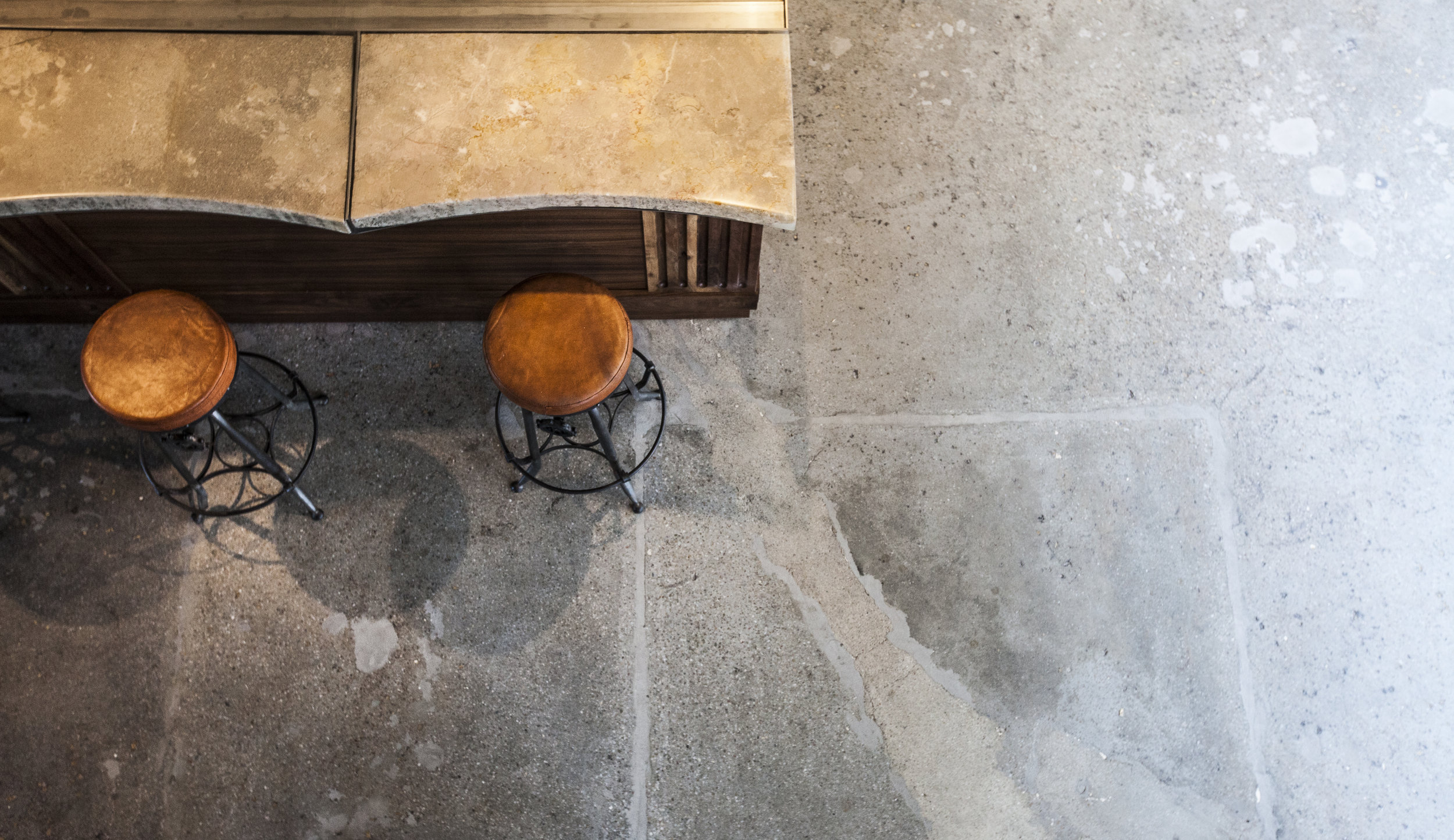  Complementing the floor original concrete floors that celebrate the space's history, a limestone bar top encased in resin.&nbsp;Bringing out the beautiful raw details of the stone,&nbsp;tt also provides a durable surface for the bar and cafe patrons