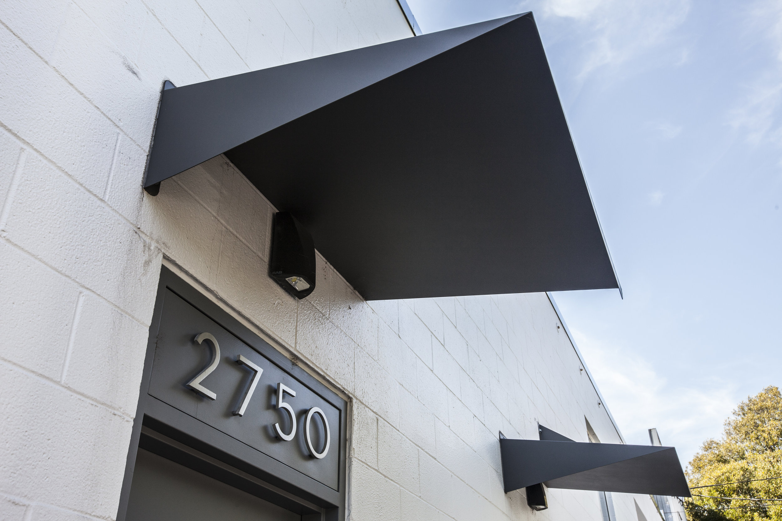 Clean discrete numbers over the doors and with custom bent steel awnings. These subtle details are discrete as this is a private building.