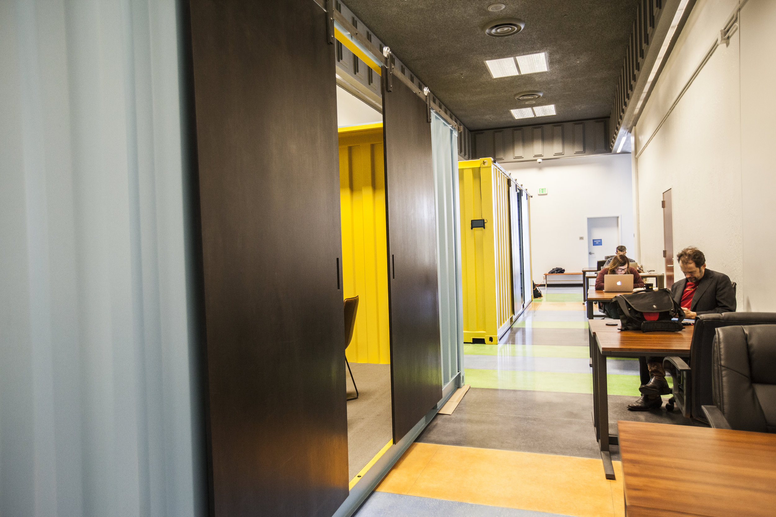  Brightly colored shipping container conference rooms with sliding doors now fill the large hallway. 