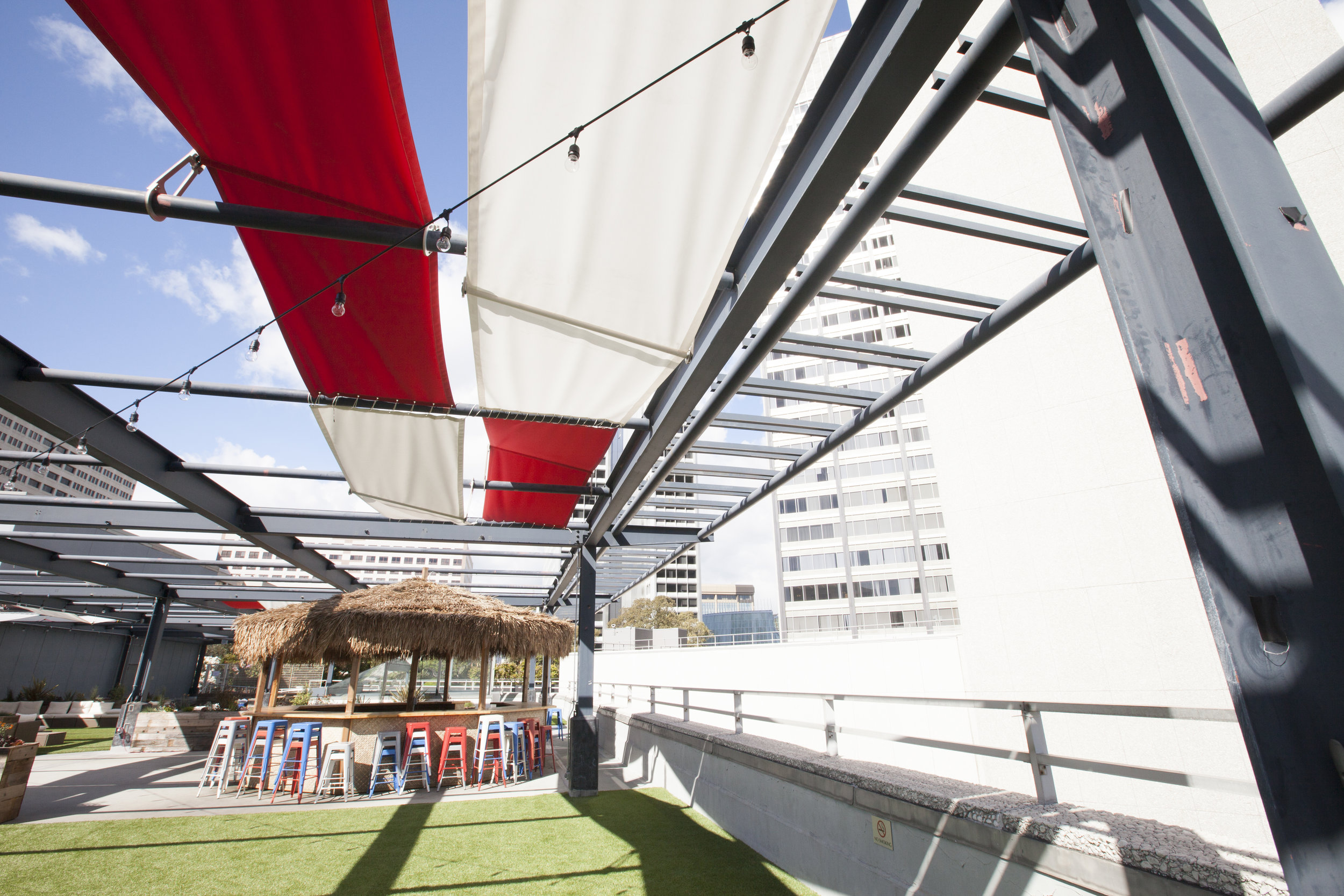  We designed an awning hanging system in red and white. The brackets add angles to the awnings allowing for different sun/shade options and visual interest. 