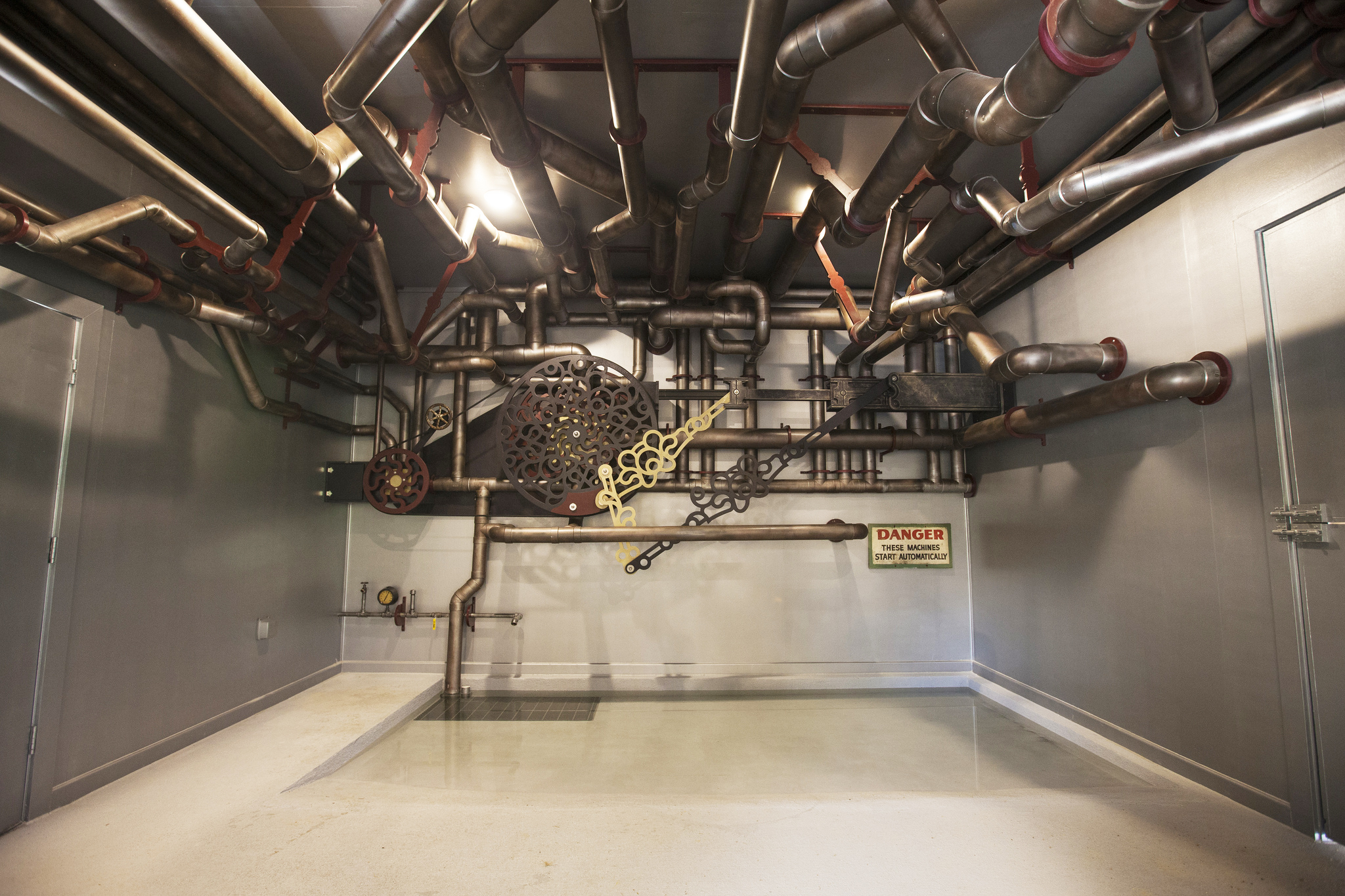 The pool for the tortoise to soak in sits below a decorative ceiling of pipes. Some of the pipes are being used to run water and drip water into the pool, as the large tortoise likes that.