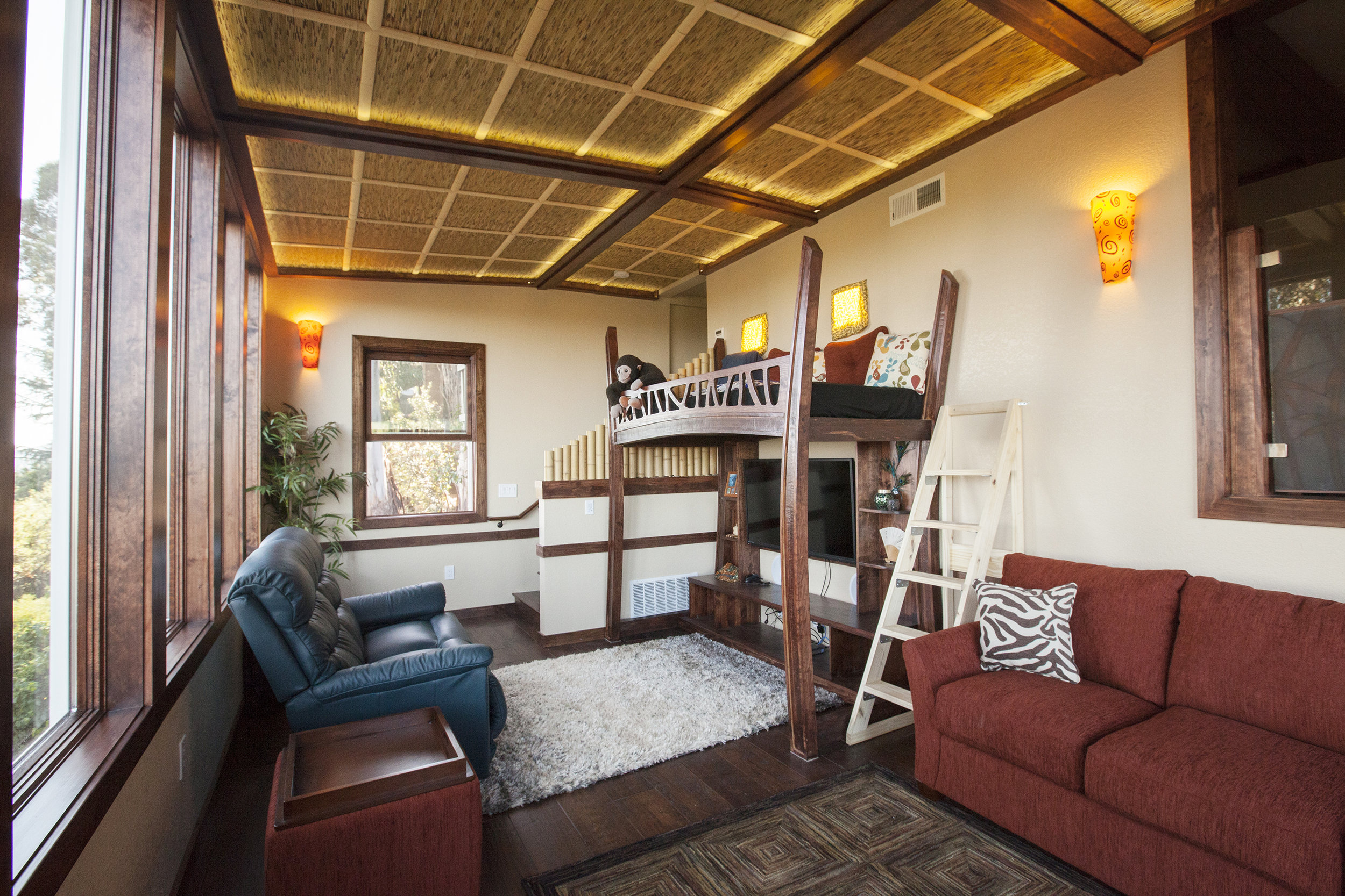  The new den has a 'kitchy' tropical theme with a thatch ceiling, dark wood flooring and window frames, a bamboo railing and fun loft bed. 