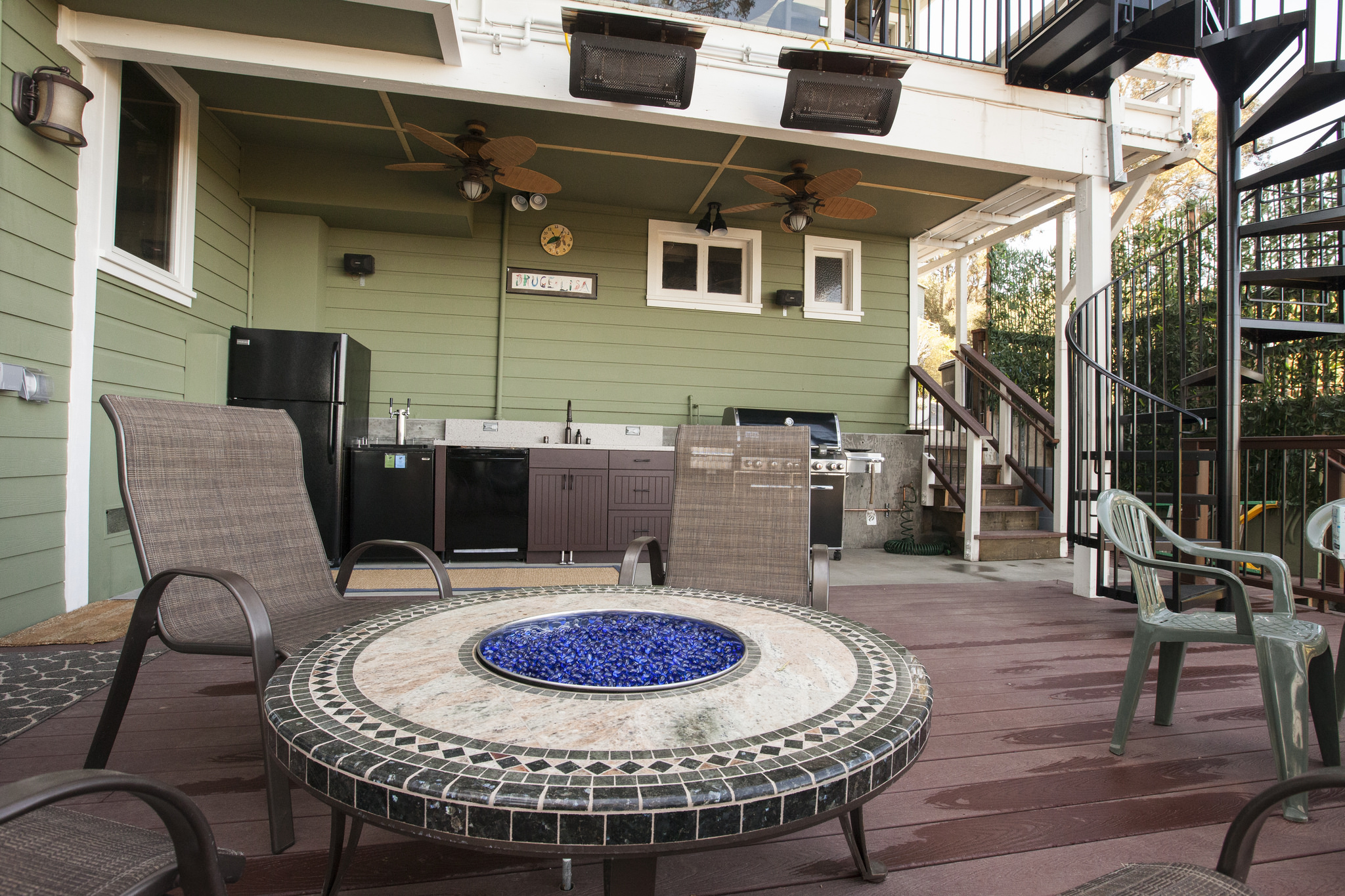  With all the additional space, a fun fire pit is added to the deck. In the background the spiral staircase and new outdoor kitchen can be seen. 