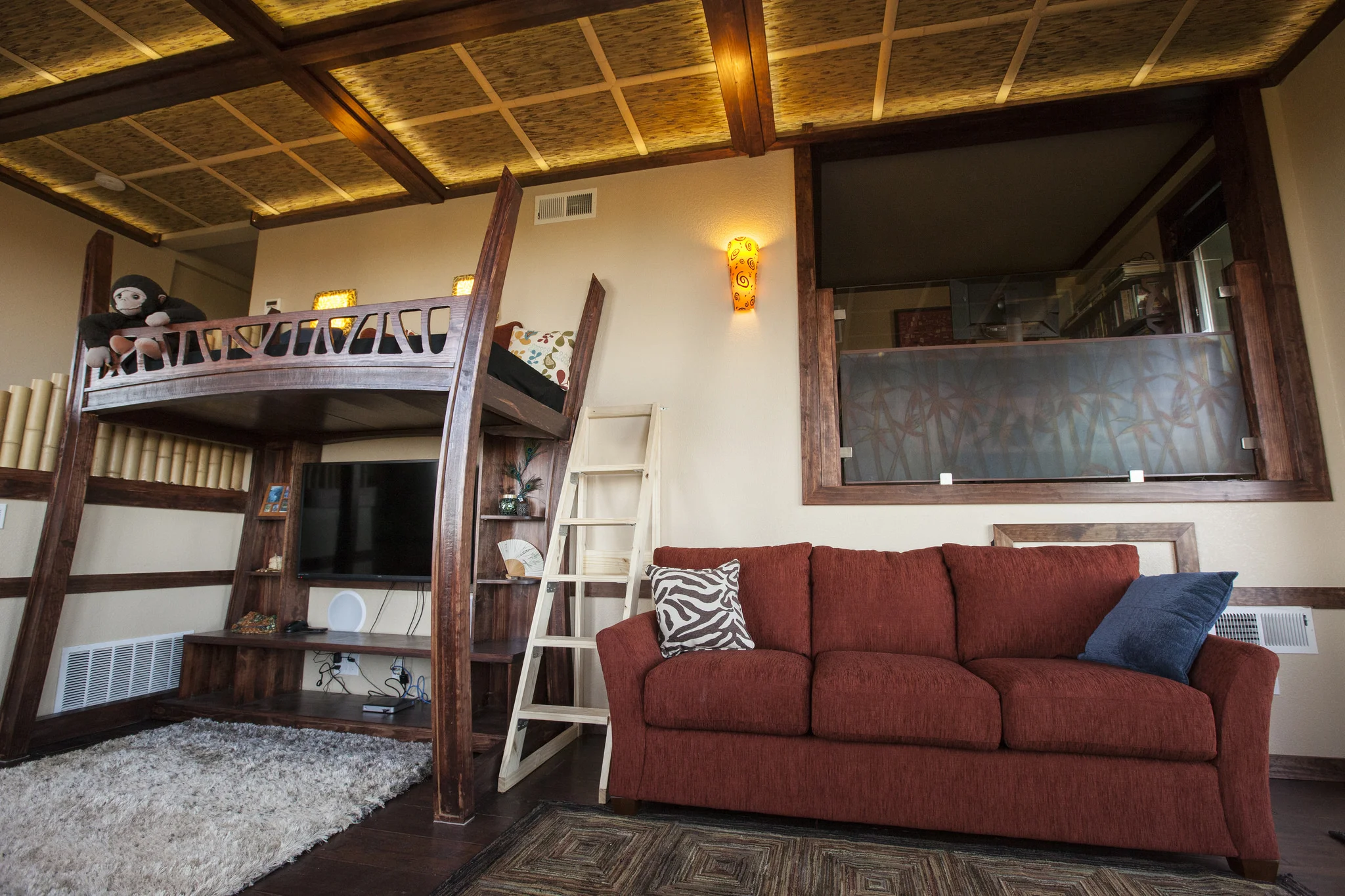 The renovated den with a window to the next level office. A pull out couch for guests and a loft bed for the kids with a fun ladder.