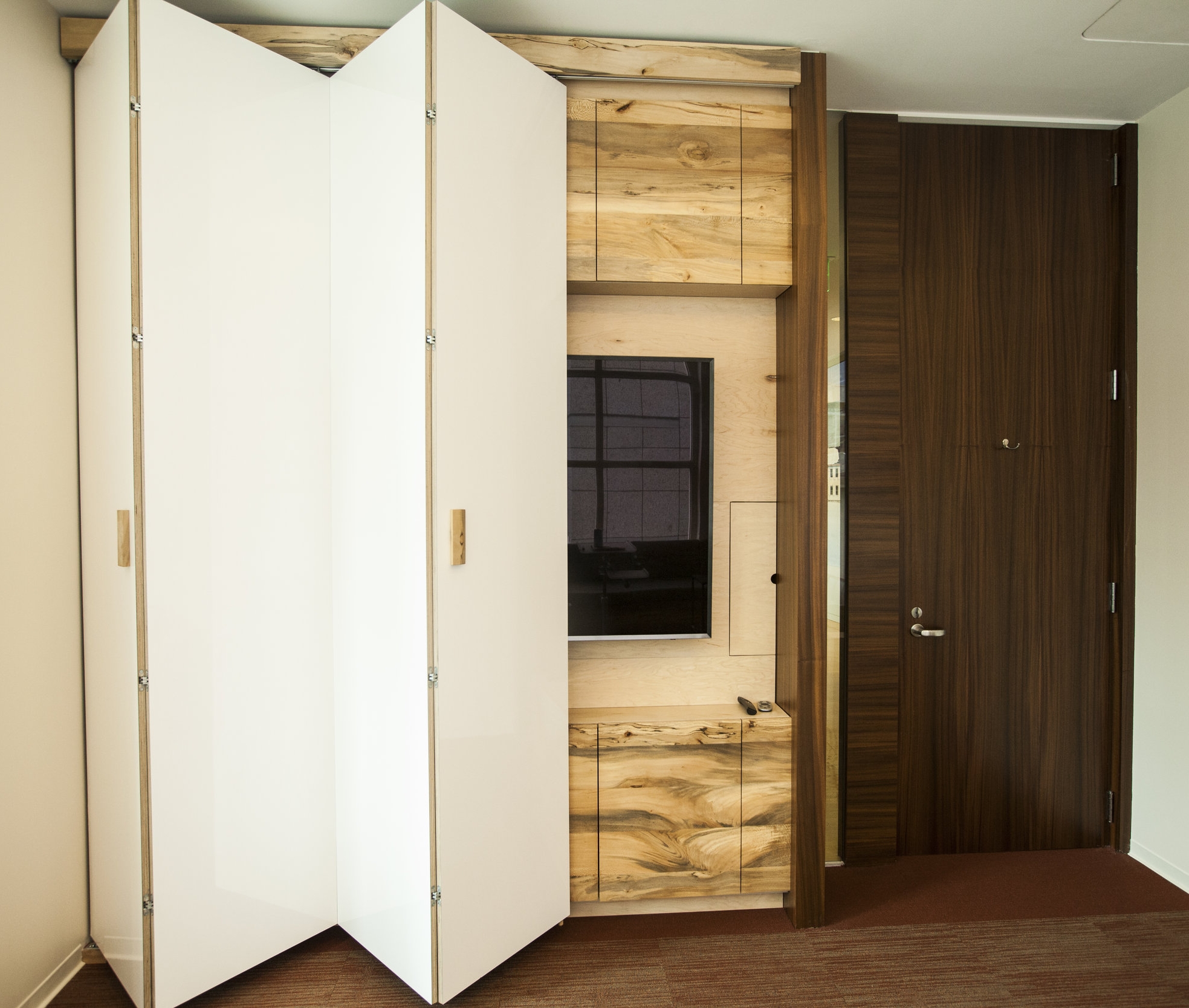  Accordion opening door reveals a beautiful sycamore paneled cabinet behind with storage and a large flat screen. 