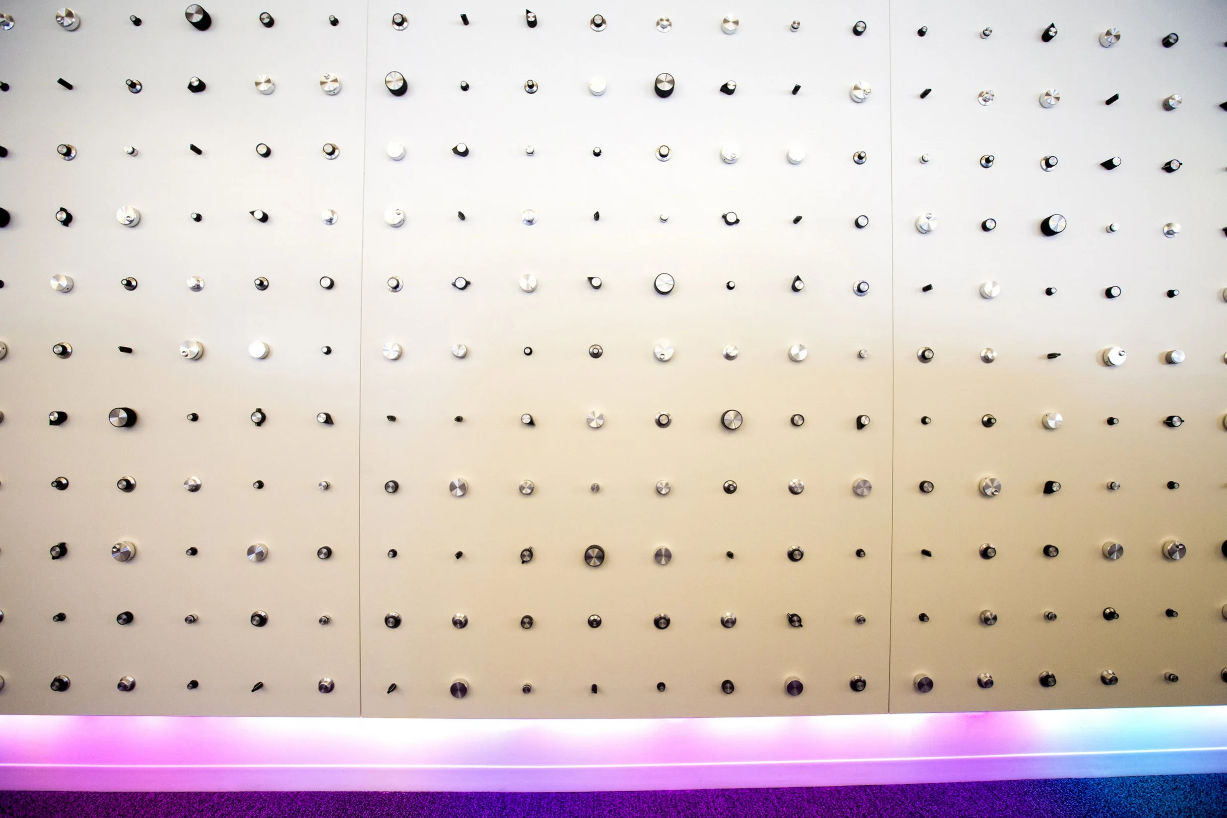 A seemingly random disbursement of knobs. Spanning down the entirety of a 40ft wall, the 8ft high Knob Wall is an interactive art piece. The LEDs on the bottom are controlled with select knobs that can do multiple functions.