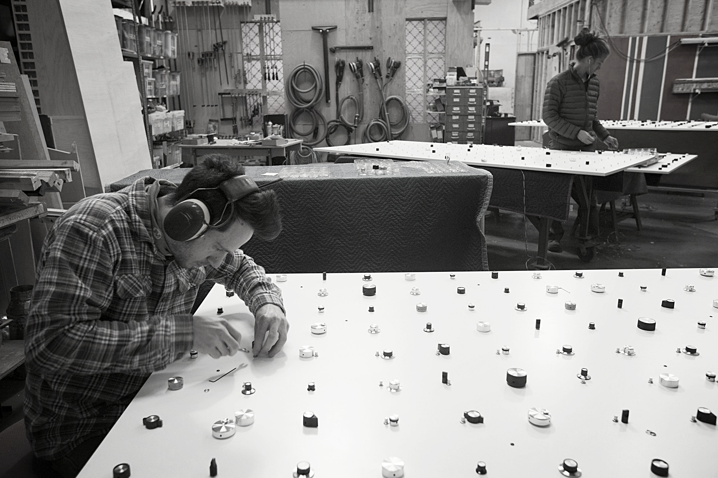  In our fabrication shop,&nbsp;one by one, Joel attaches the 1287 knobs across the ten 8ft tall panels. 