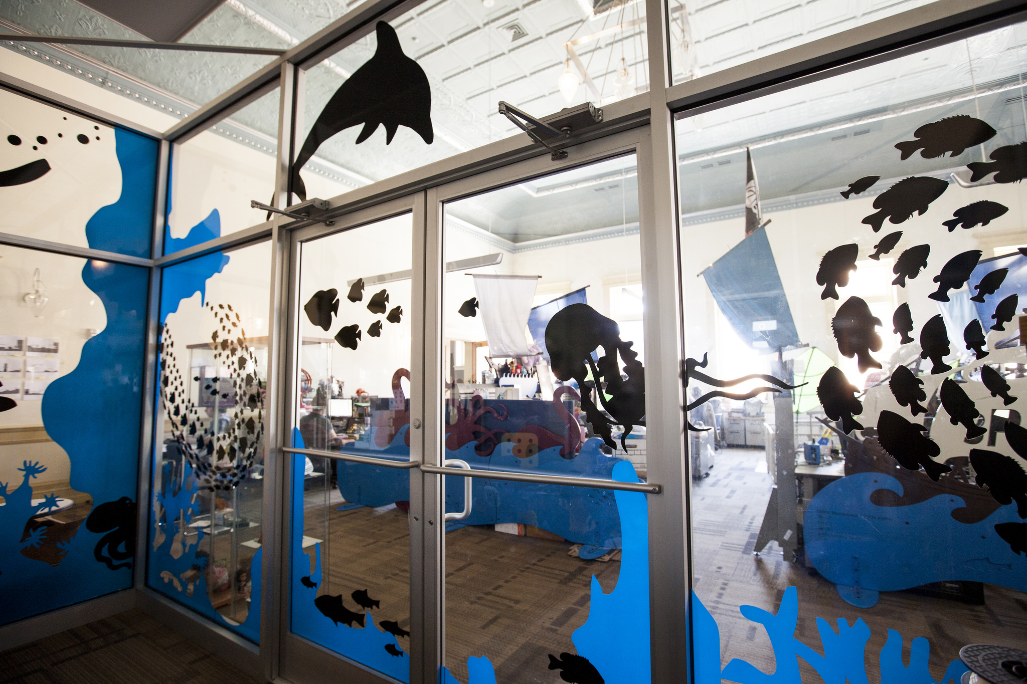  In the center of the open office stands a meeting room with all glass walls that was referred to as 'the fish tank'. We playfully covered it with an under water theme of fish, coral and divers. The vinyl application adds a need privacy to the meetin