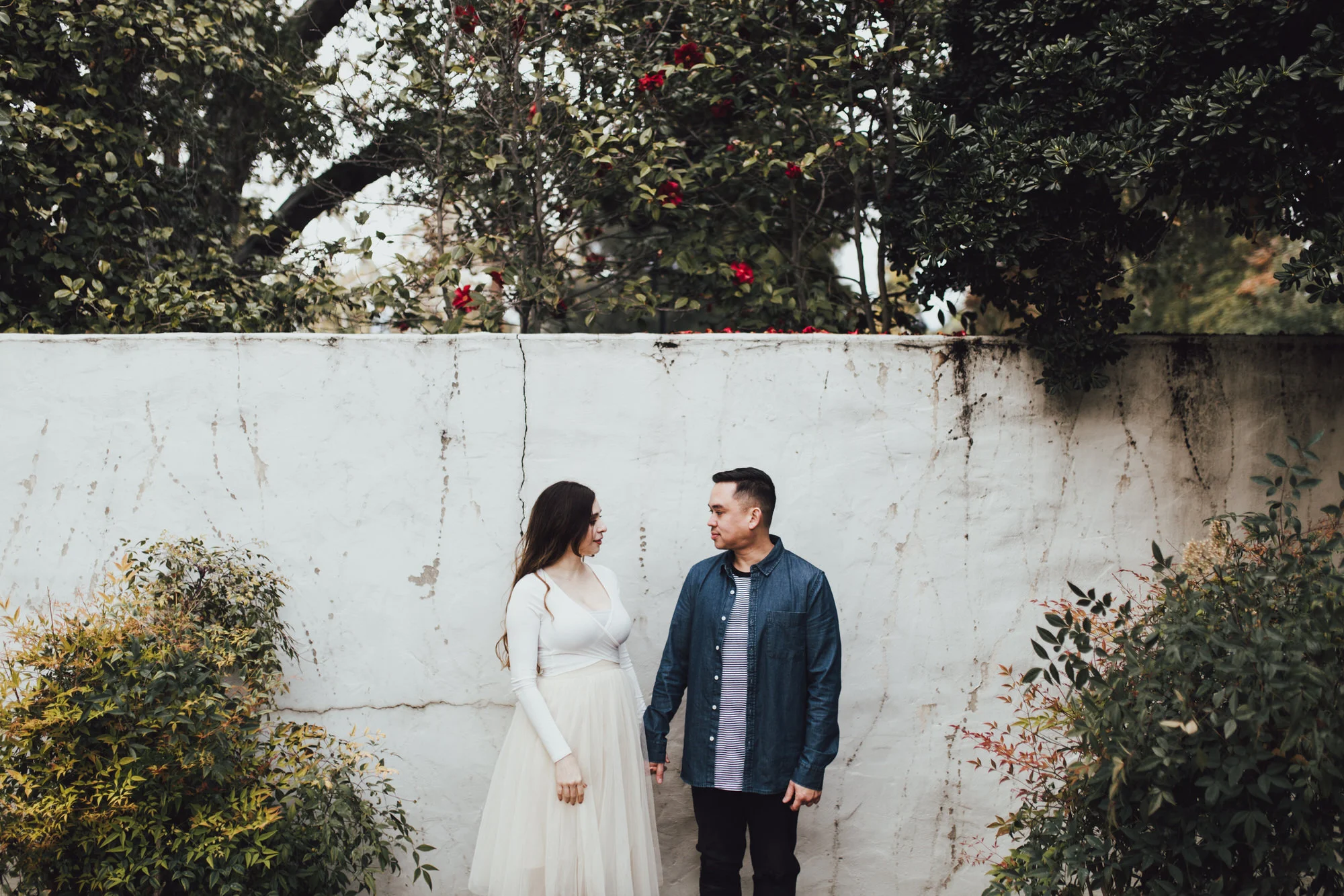 couple against textured white wall with plants