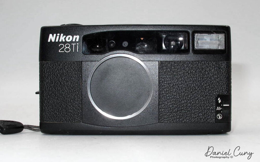 Front view of Nikon 28Ti with lens retracted, and flash controls visible.