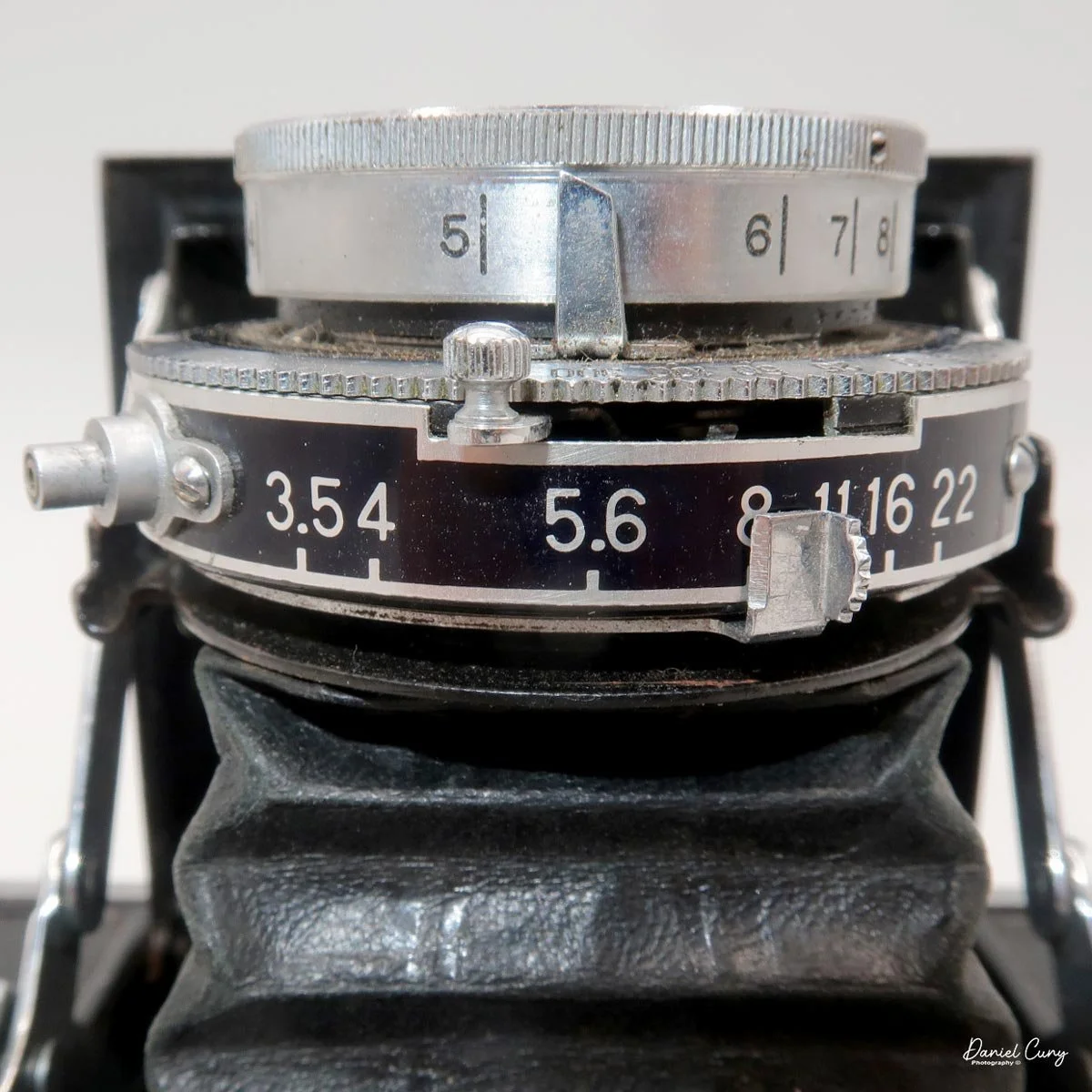 PC Port, Shutter cocking lever, Focus distance on lens, and Aperture indicator.
