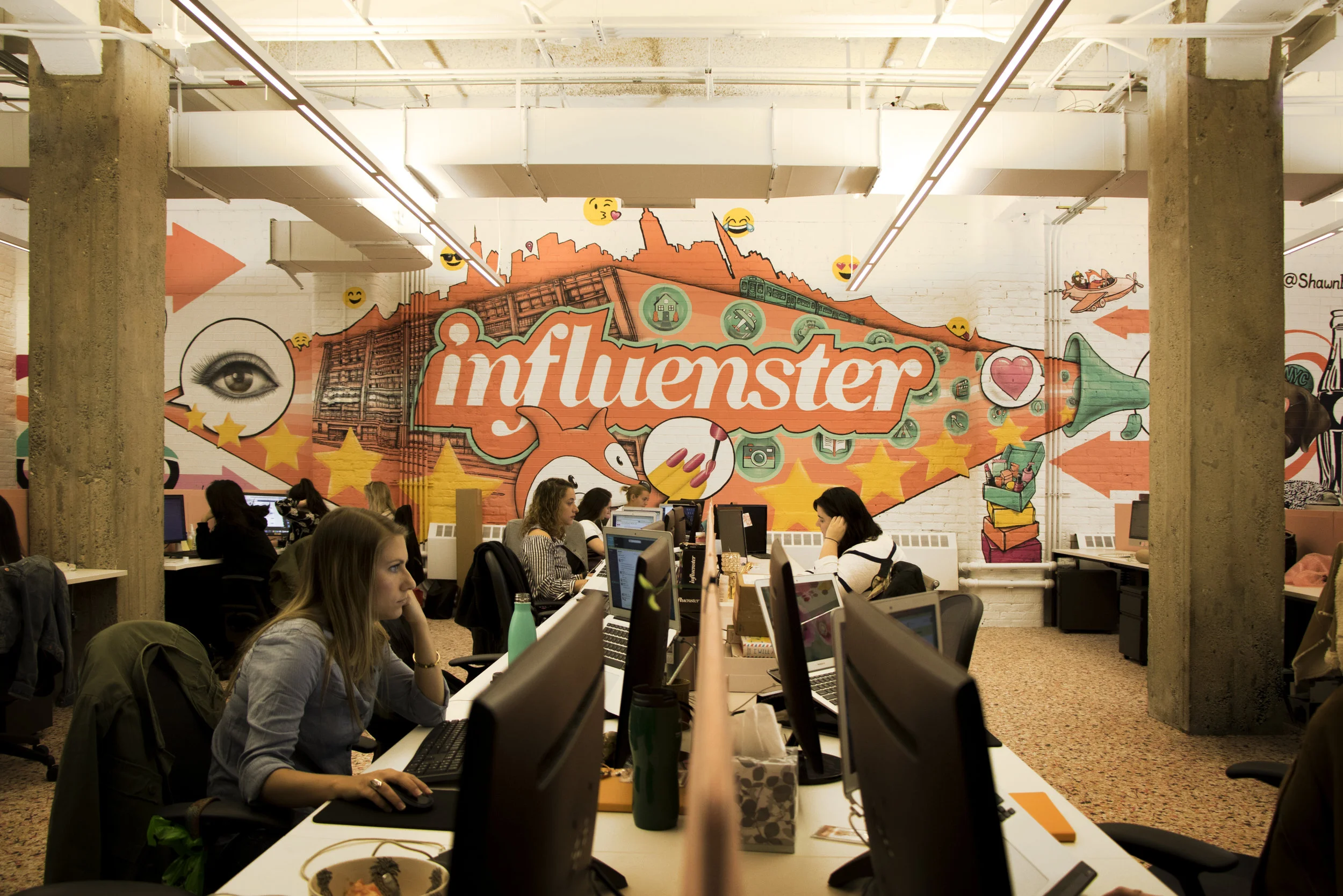 In the main office, an Influenster mural, also by Shawn Bullen, envelopes the entire wall. It is illustrated with design elements integral to the company’s foundation such as the VoxFox (Influenster’s mascot), Chaplin (the leader of the dog pack), emojis, star ratings and more. Shawn painted the exterior of the main conference room with splotches and hues of the company color, a shade of atomic tangerine, to give the space a playful touch. The open floor plan allows for the free exchange of conversations and sharing of ideas while the myriad of conference rooms and nooks allow employees to retreat to should they need to shake up their work momentum. The conference rooms are all themed based on different badges that Influenster offers its members: beauty, fashionista, techie, etc. Badges are offered to members based on their activity on the platform aligned with their preferences and interests. Similarly, each room is designed based on each lifestyle bucket, e.g., the fitness room is decked out with weights, medicine ball chairs and rocking chairs to keep occupants of the room active and fit. The library located in the northern wing of the office is filled with professional development resources for employees to keep learning and growing. They can climb up the rolling ladder, find a title that they are looking for, and relax in the quiet alcove with a book in hand.