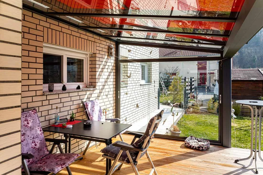Tisch unter einer Terrassenüberdachung mit seitlicher Glas Schiebetür
