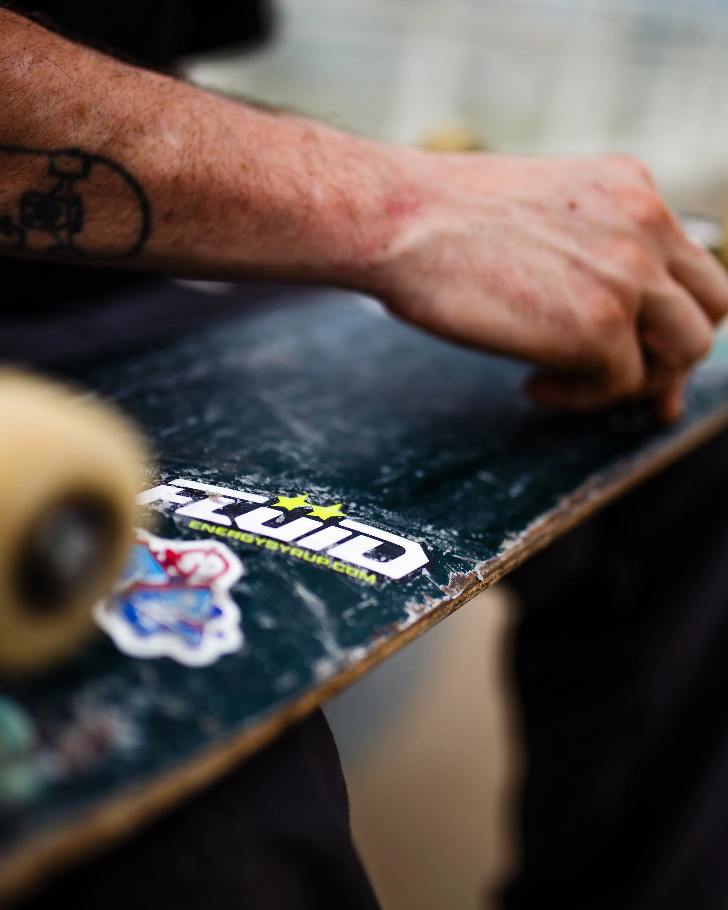 Close-up of a person working on a skateboard with a FLUID logo sticker on the deck