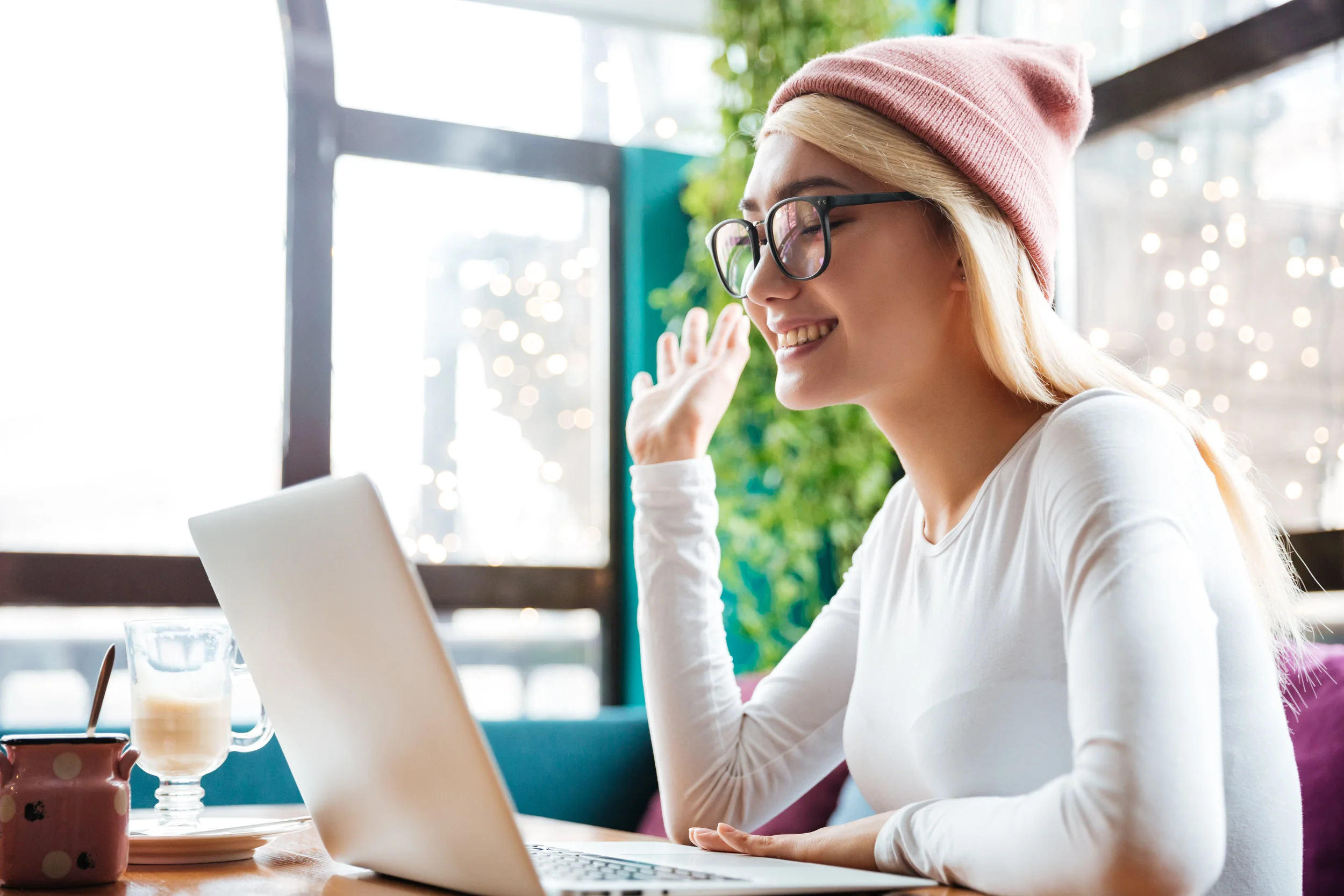 graphicstock-smiling-young-woman-in-hat-and-glasses-using-laptop-and-making-video-call-in-cafe_Hkx-tOCal.jpg